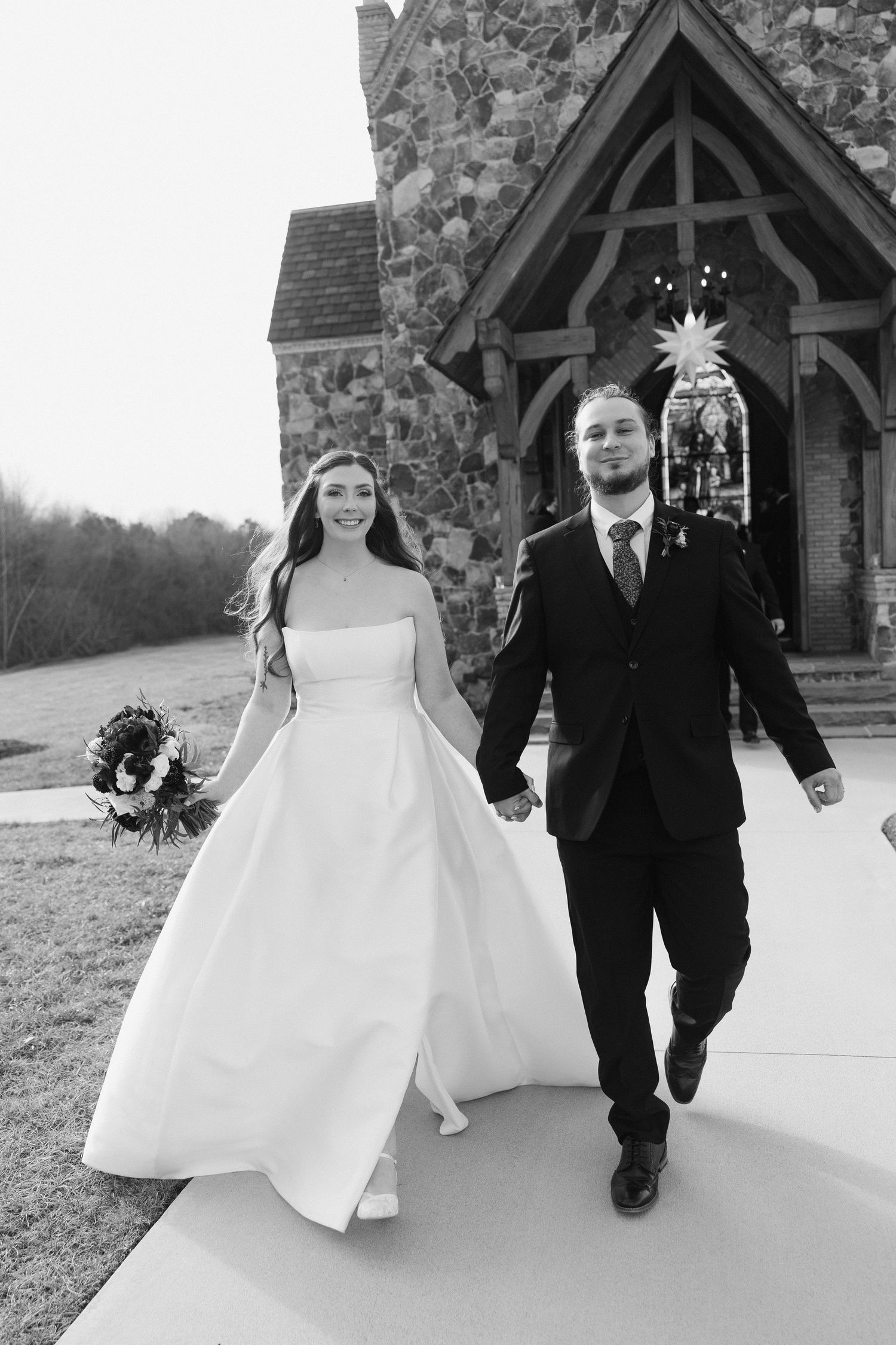 A series of black and white wedding photos showing a couple walking together outside a stone church building.