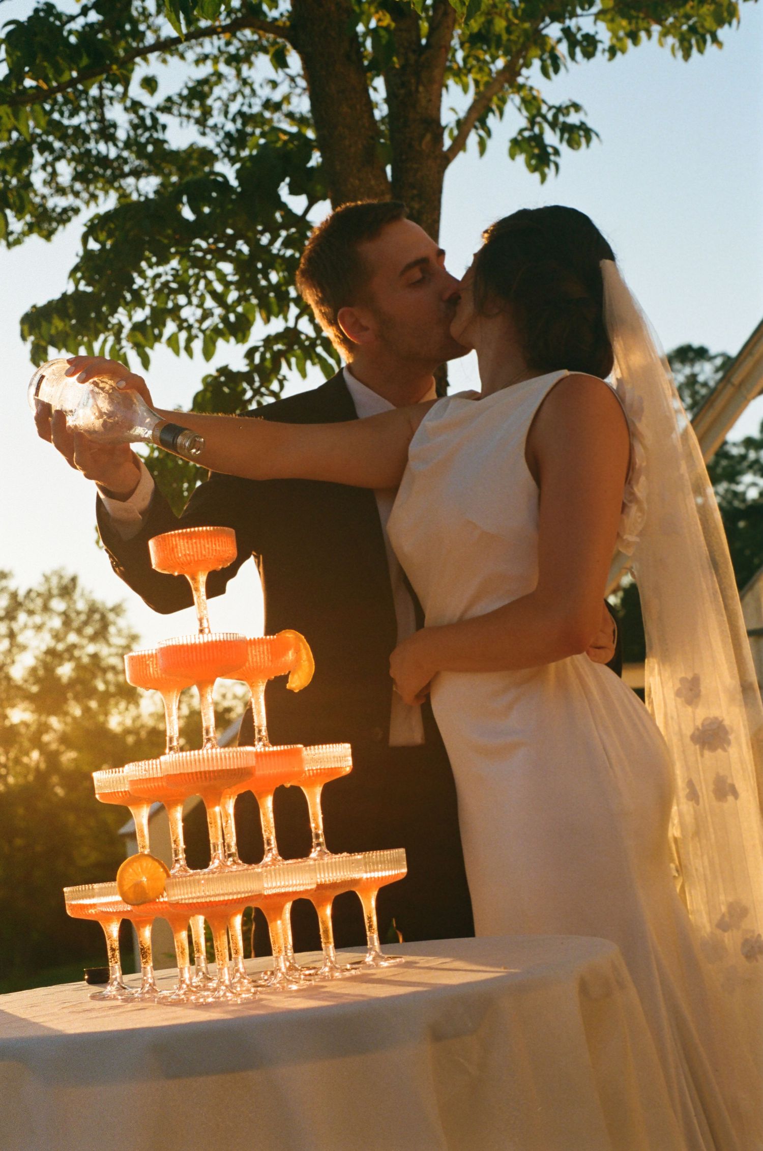 Glowing champagne glasses on a wedding reception table captured during golden hour sunset, editorial wedding photographer in Raleigh NC