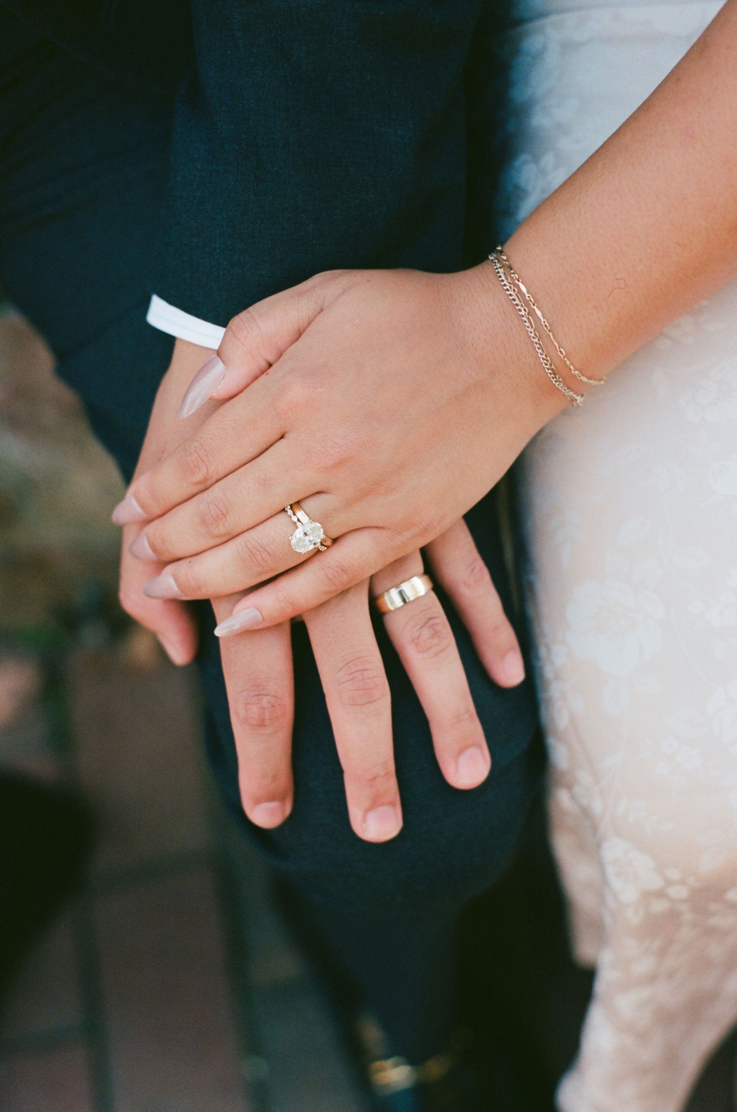 Close-up sequence of hands showing off delicate engagement ring and wedding band jewelry against dark background.