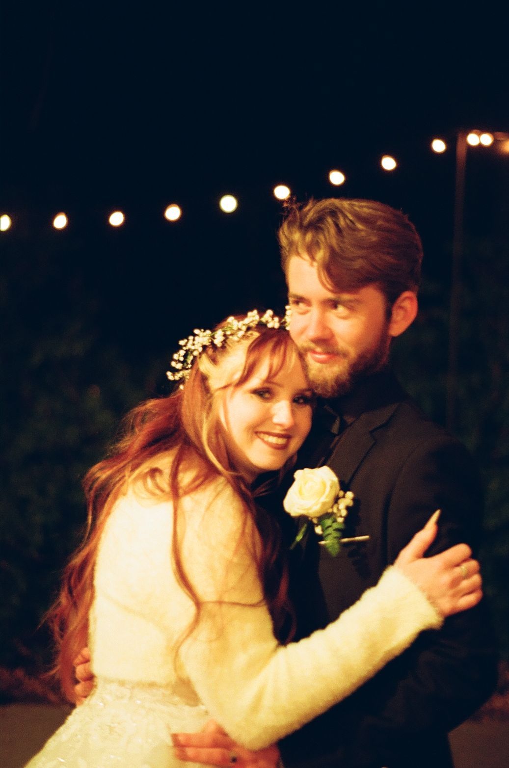 A wedding couple dances together under string lights during their evening reception celebration on 35mm film and super 8 in Charlotte NC