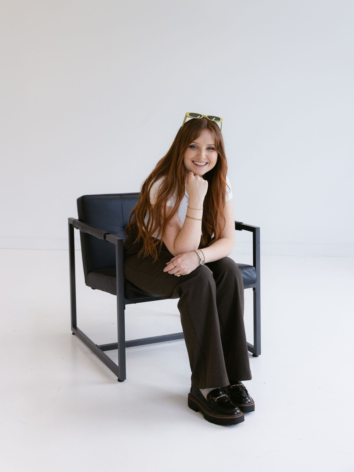 Four sequential photos show someone in black attire posing on a modern minimalist bench against a white backdrop.