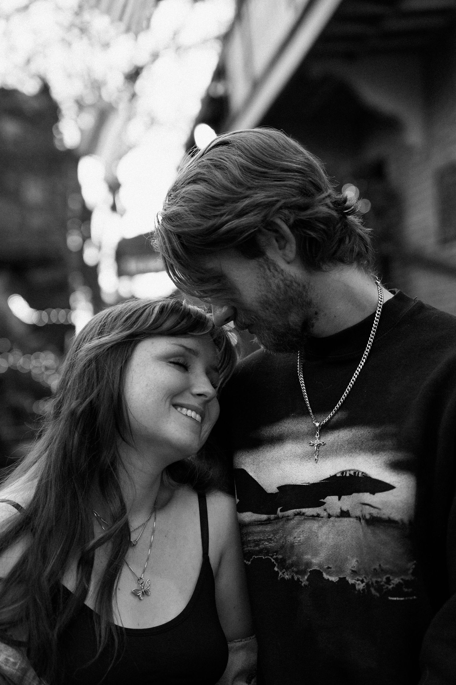 A romantic black and white portrait of a couple sharing an intimate moment, with him wearing a t-shirt with an airplane design.
