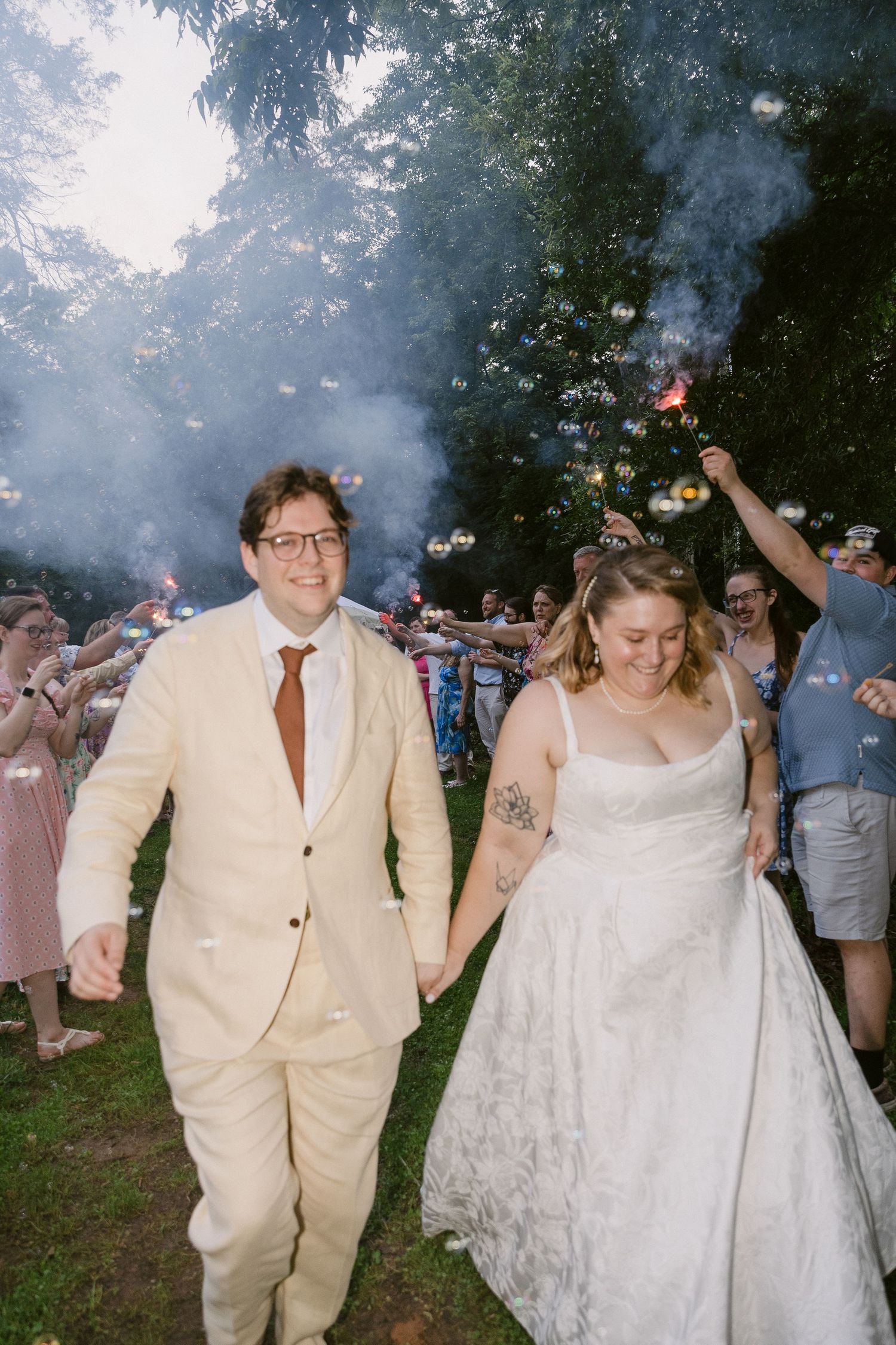 A newlywed couple walks together under smoke and sparklers at an outdoor wedding celebration in Rock Hill SC, Documentary Wedding Photograph