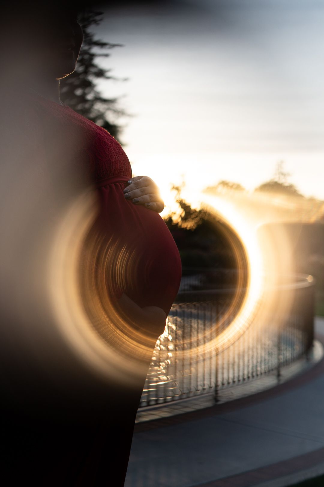 Creative maternity photo idea of light rings created by sunset highlight the baby bump among roses in San Jose by pixels by pari