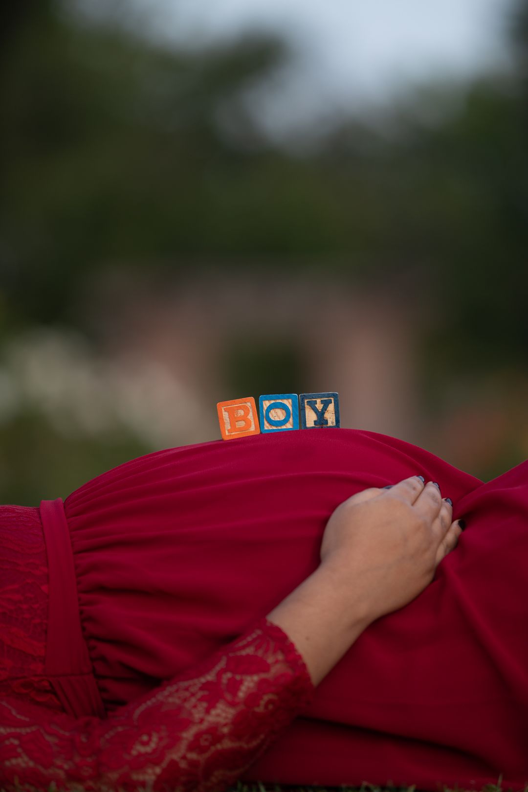 Maternity shoot pose idea in grass fields at San Jose Rose Garden announcing baby boy with wood blocks