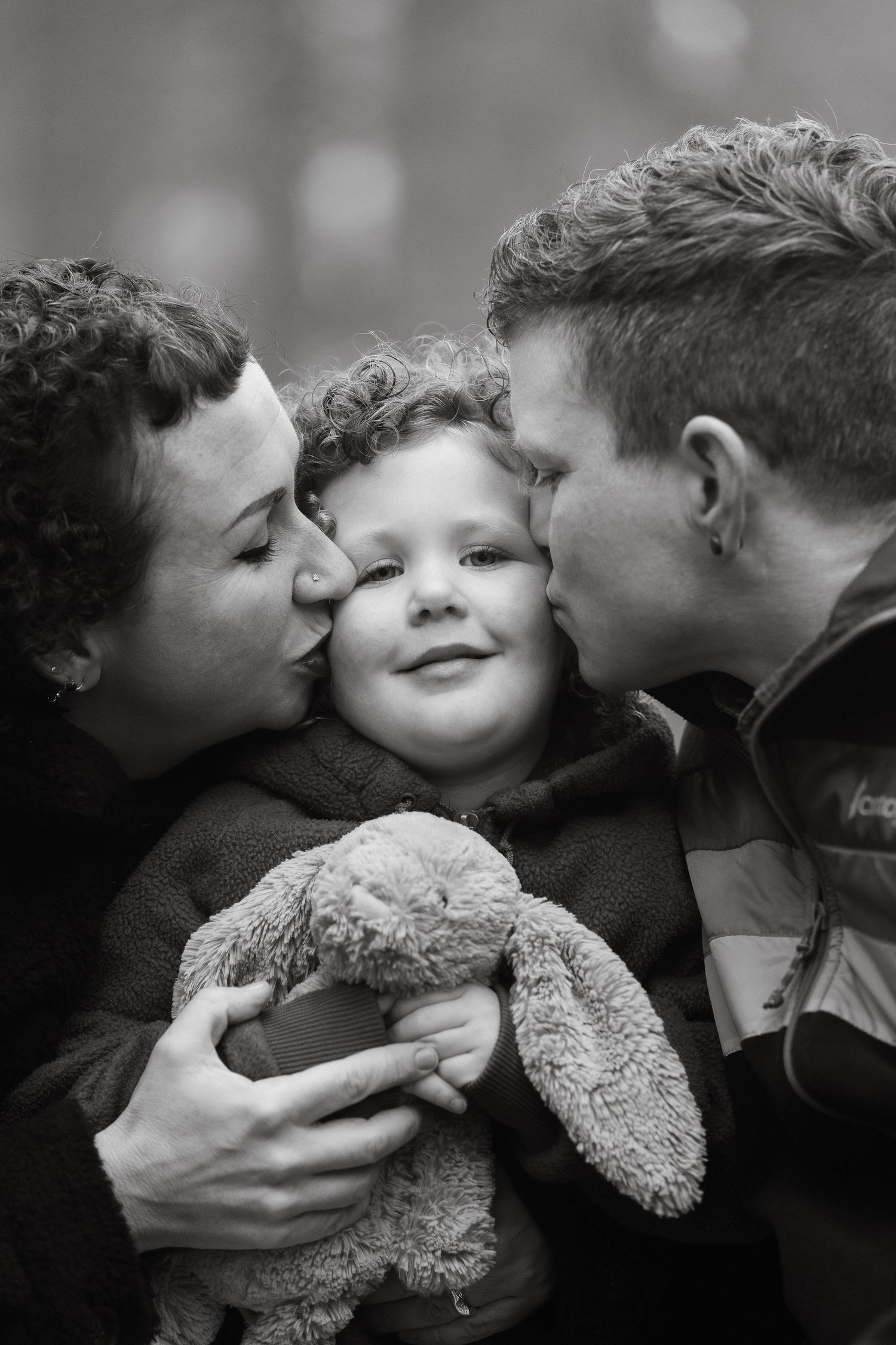 A loving family embraces in a group hug, with parents tenderly kissing their daughter, showcasing affection and unity