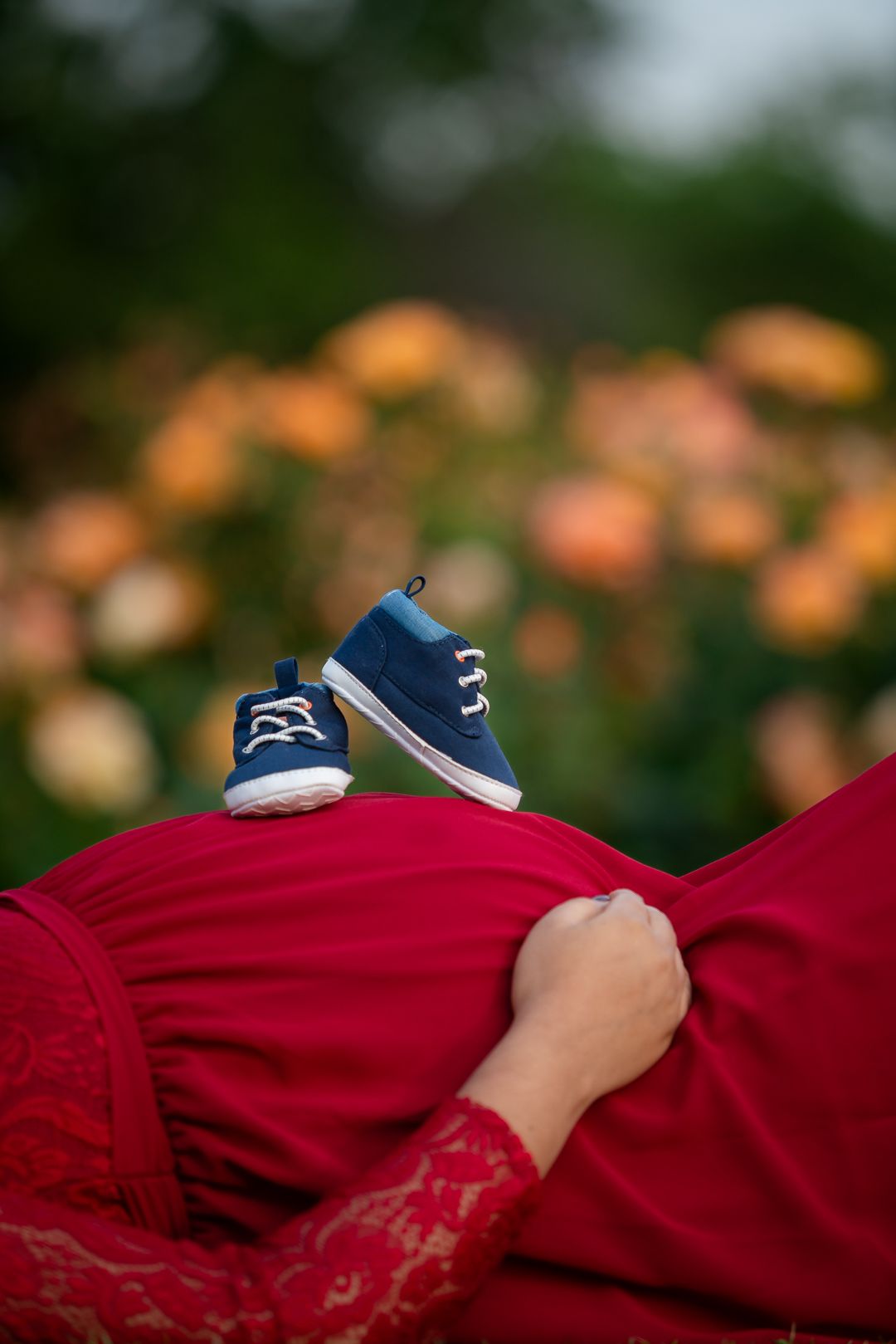 Maternity shoot pose idea in grass fields at San Jose Rose Garden announcing baby boy with blue shoes