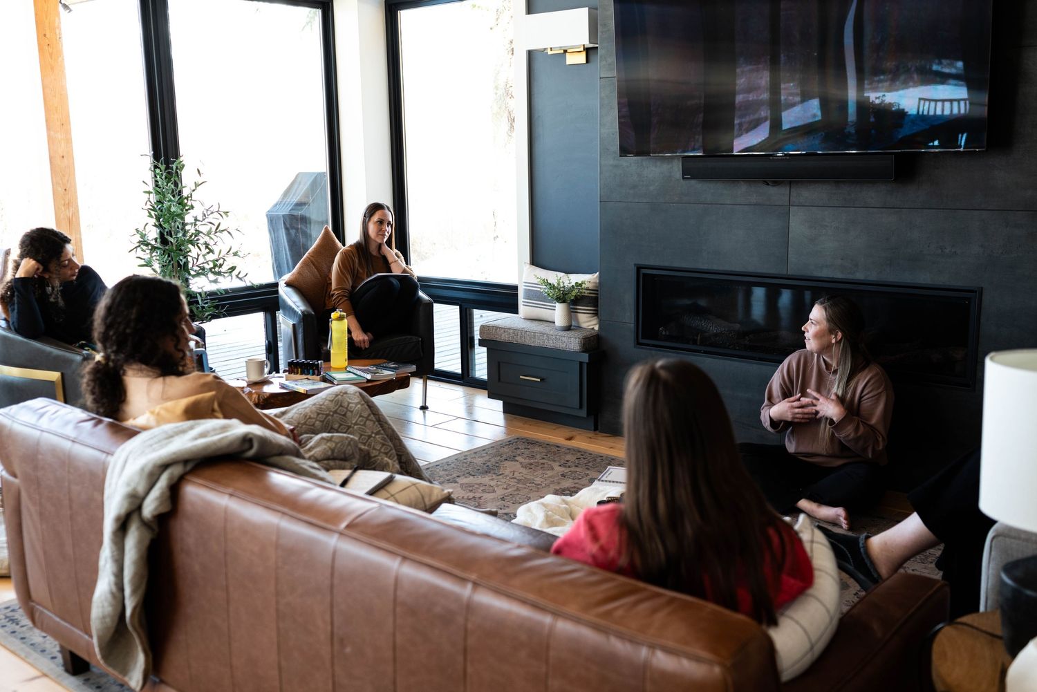 Group of people gathered on leather couch for casual indoor meeting or discussion.