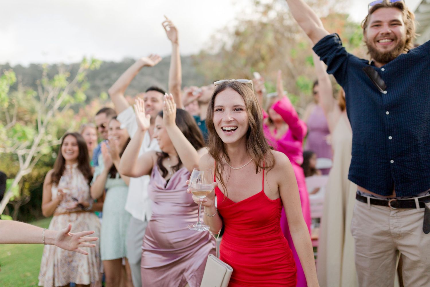Wedding guests dancing and celebrating at an outdoor reception with people in formal attire enjoying the festivities.