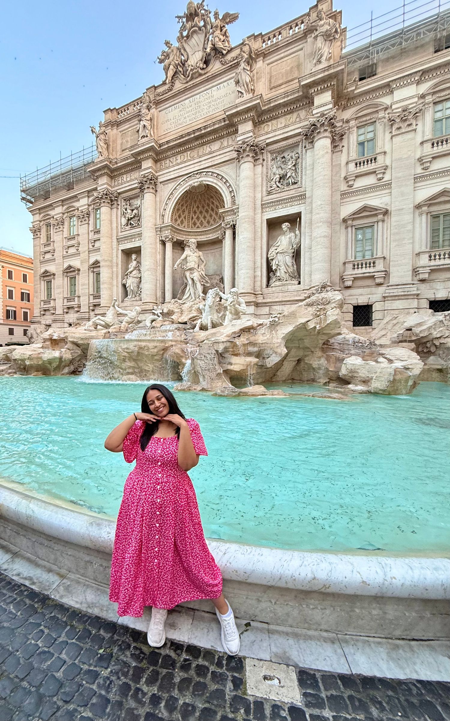 destination wedding elopment photographer Woman in pink floral dress posing in front of the iconic Trevi Fountain in Rome, Italy.