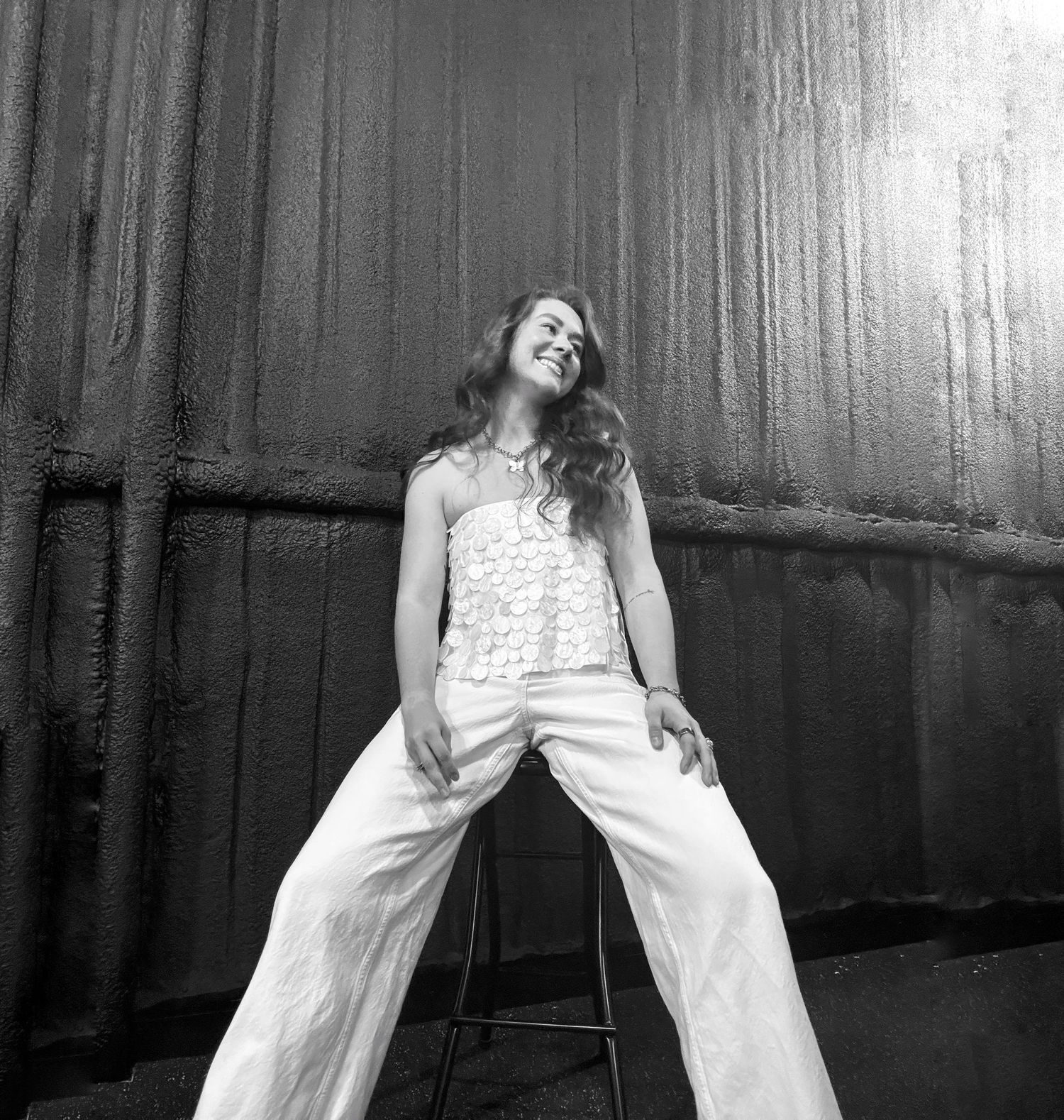 Black and white portrait of a person in white clothing posing against a dark background.