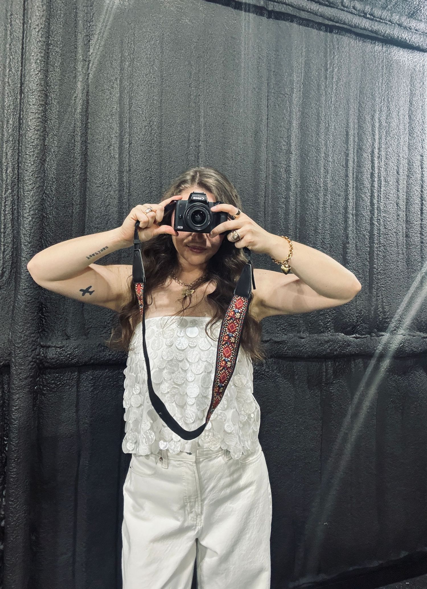 A series of four photos showing someone taking pictures with a camera against a dark backdrop.