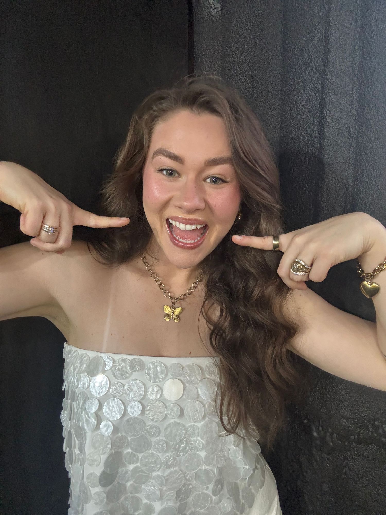 A person in a white lace top poses expressively against a dark background in a series of connected photos.