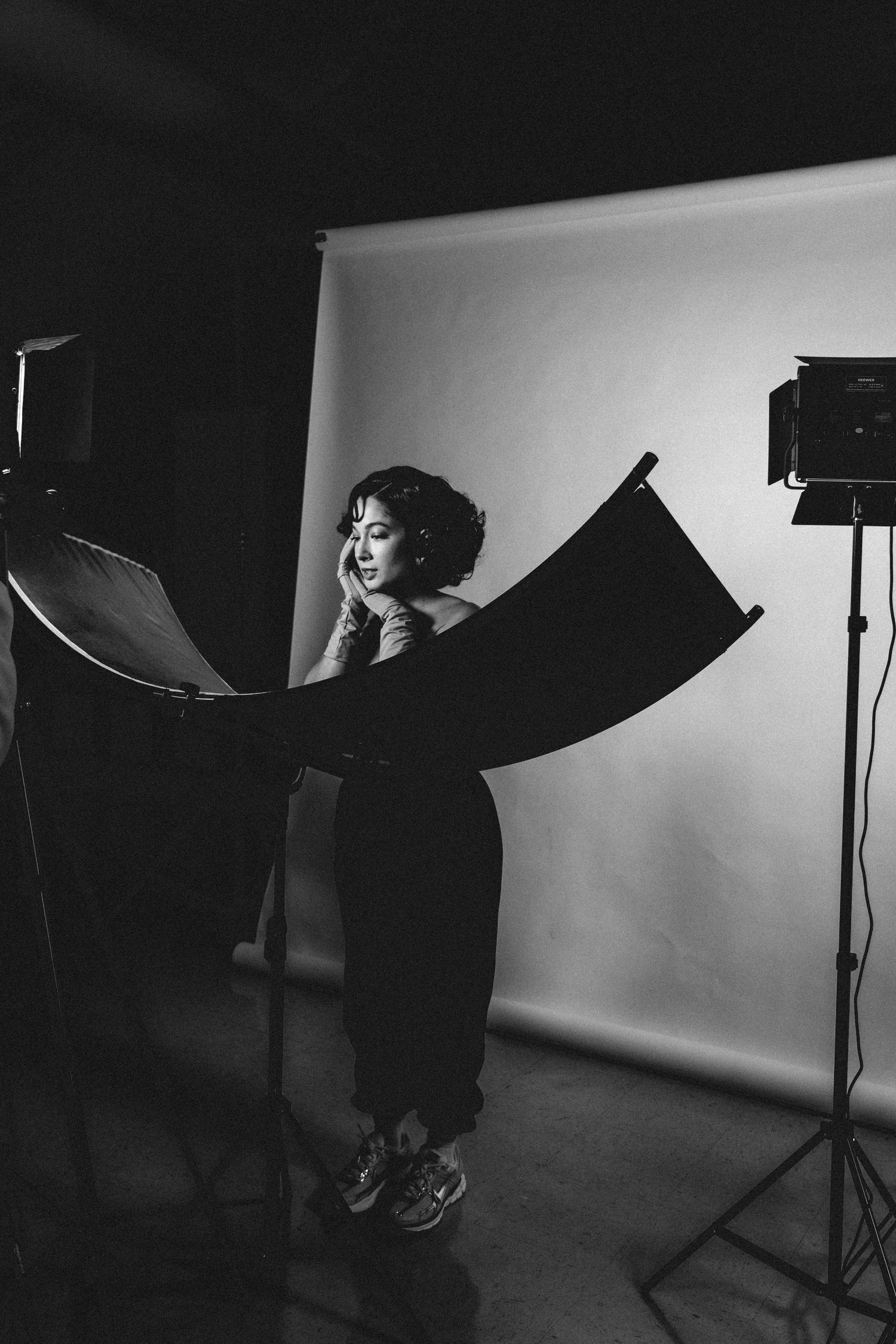 Black and white photo of a woman posing in a photography studio with professional lighting equipment.