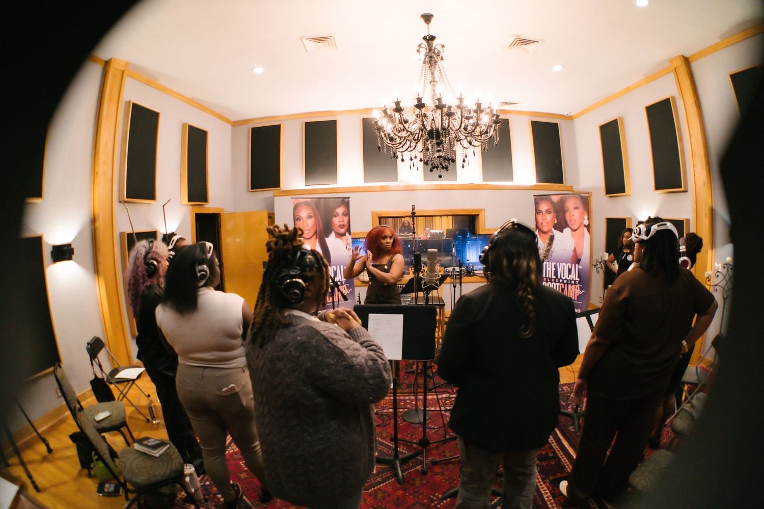 Fisheye view of a group recording session in an ornate studio with chandelier.