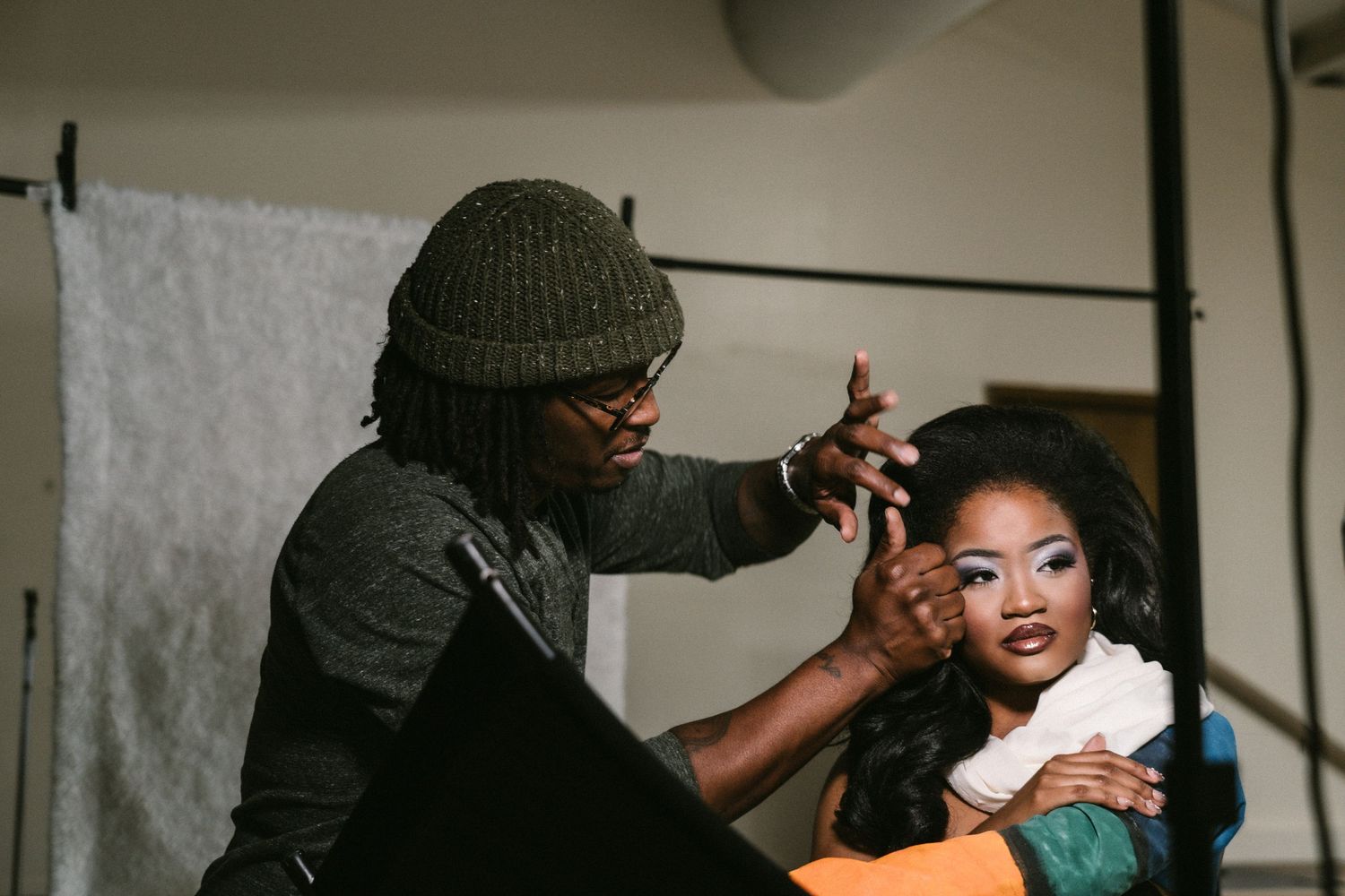 Makeup artist applying makeup to a model with long hair during a professional photo shoot.
