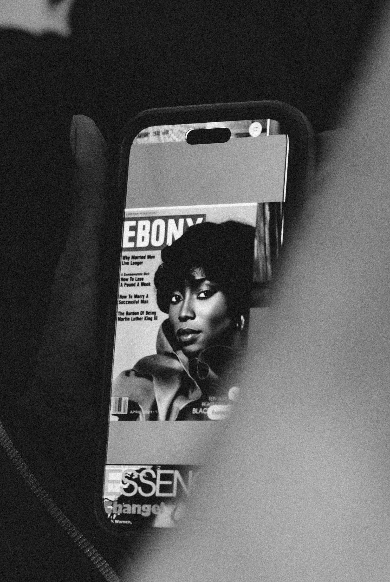 Black and white photo of a phone displaying an Ebony magazine cover featuring a woman.
