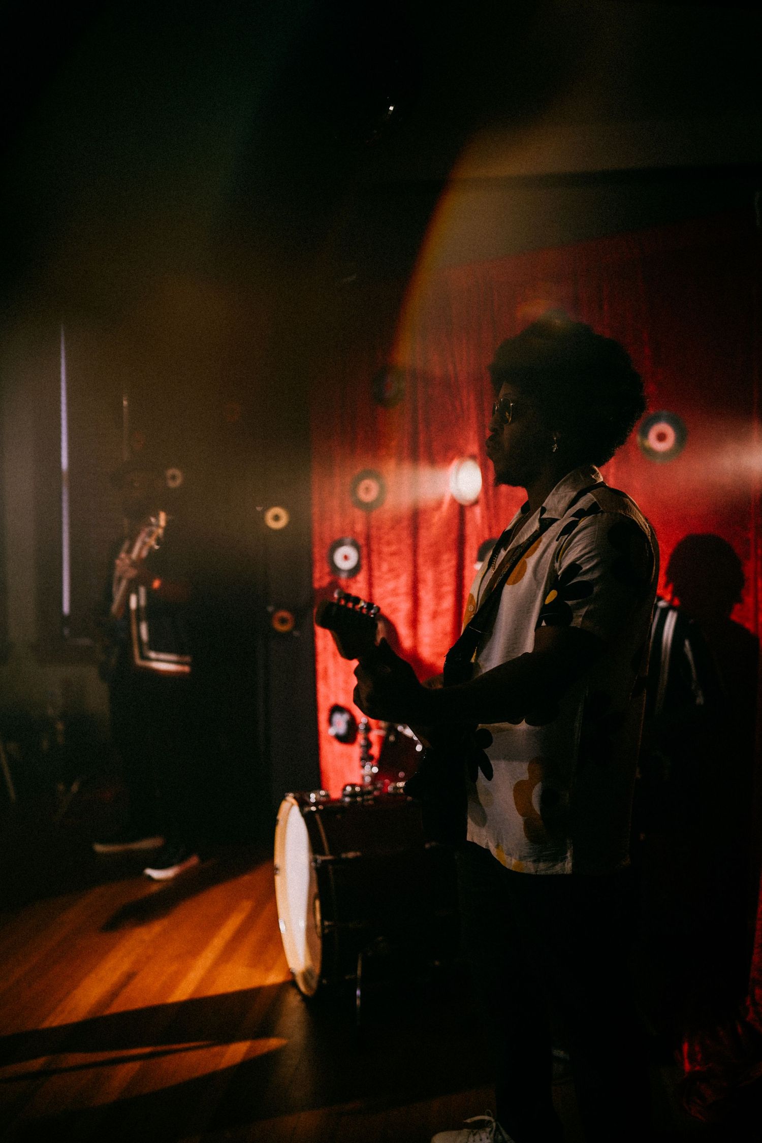 Silhouette of a guitarist performing on a dimly lit stage with red ambient lighting.