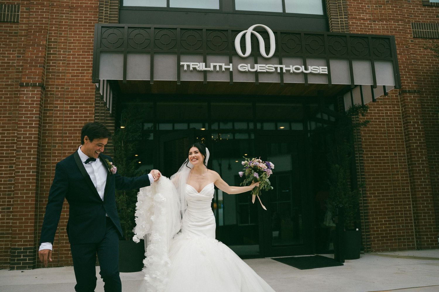 Bride and groom walking out of Truth Guesthouse venue, bride holding a bouquet and veil.