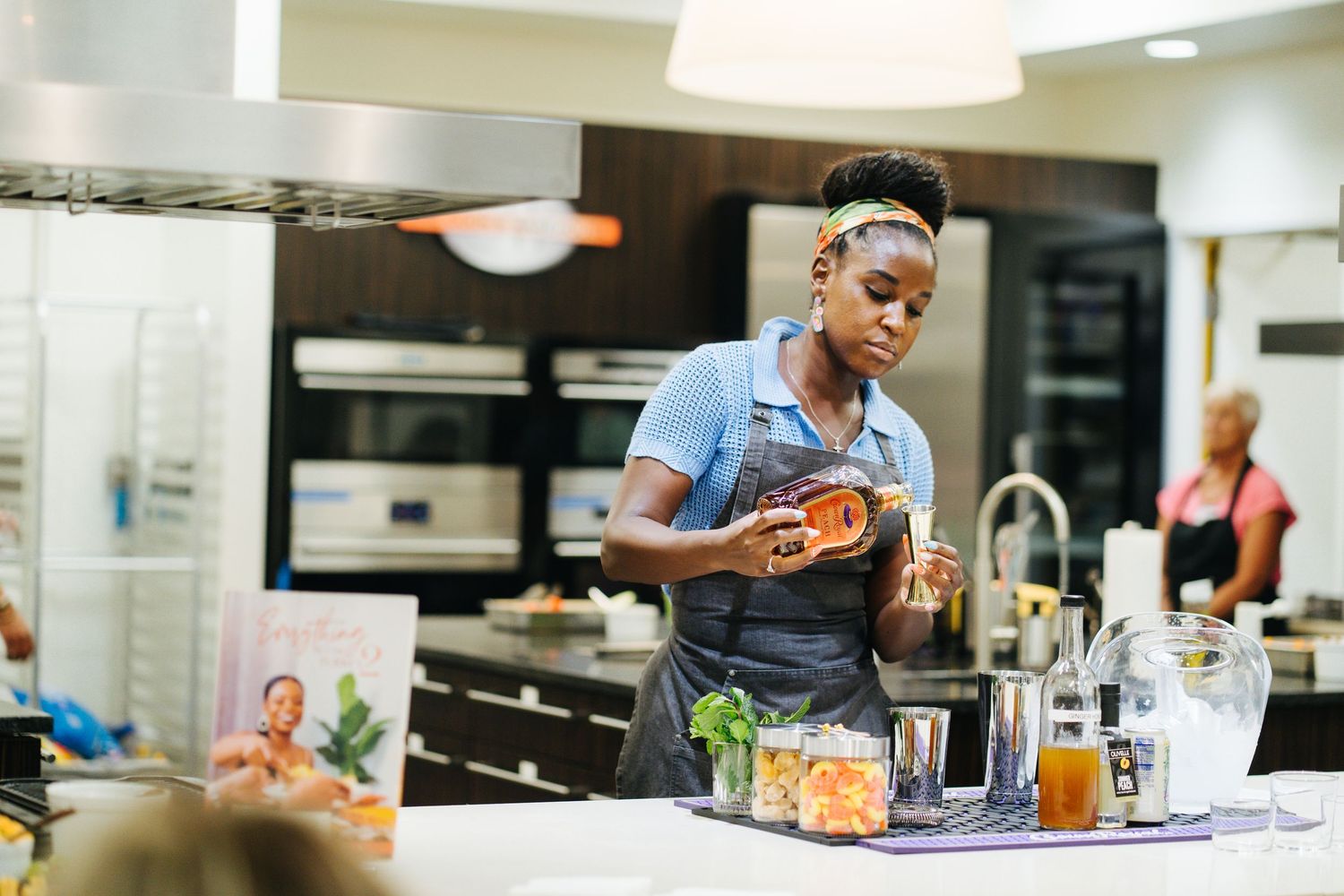 Woman in apron prepares food at a kitchen counter with ingredients.