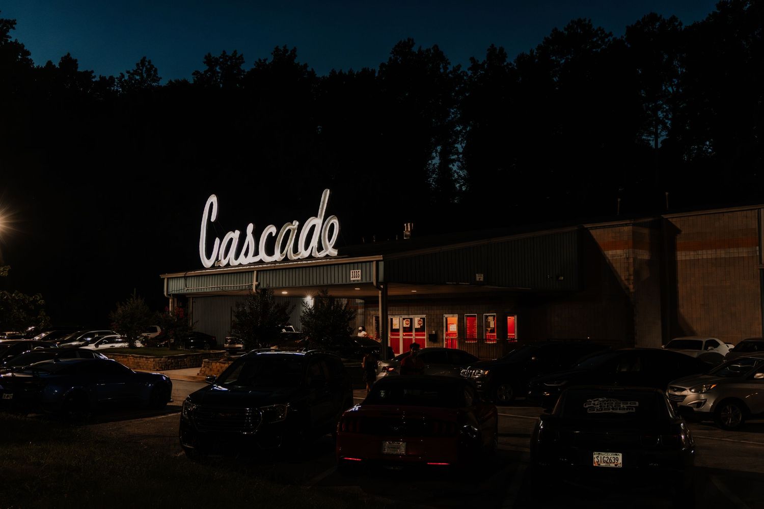 The illuminated Cascade sign glows above a building entrance surrounded by a dark night sky.