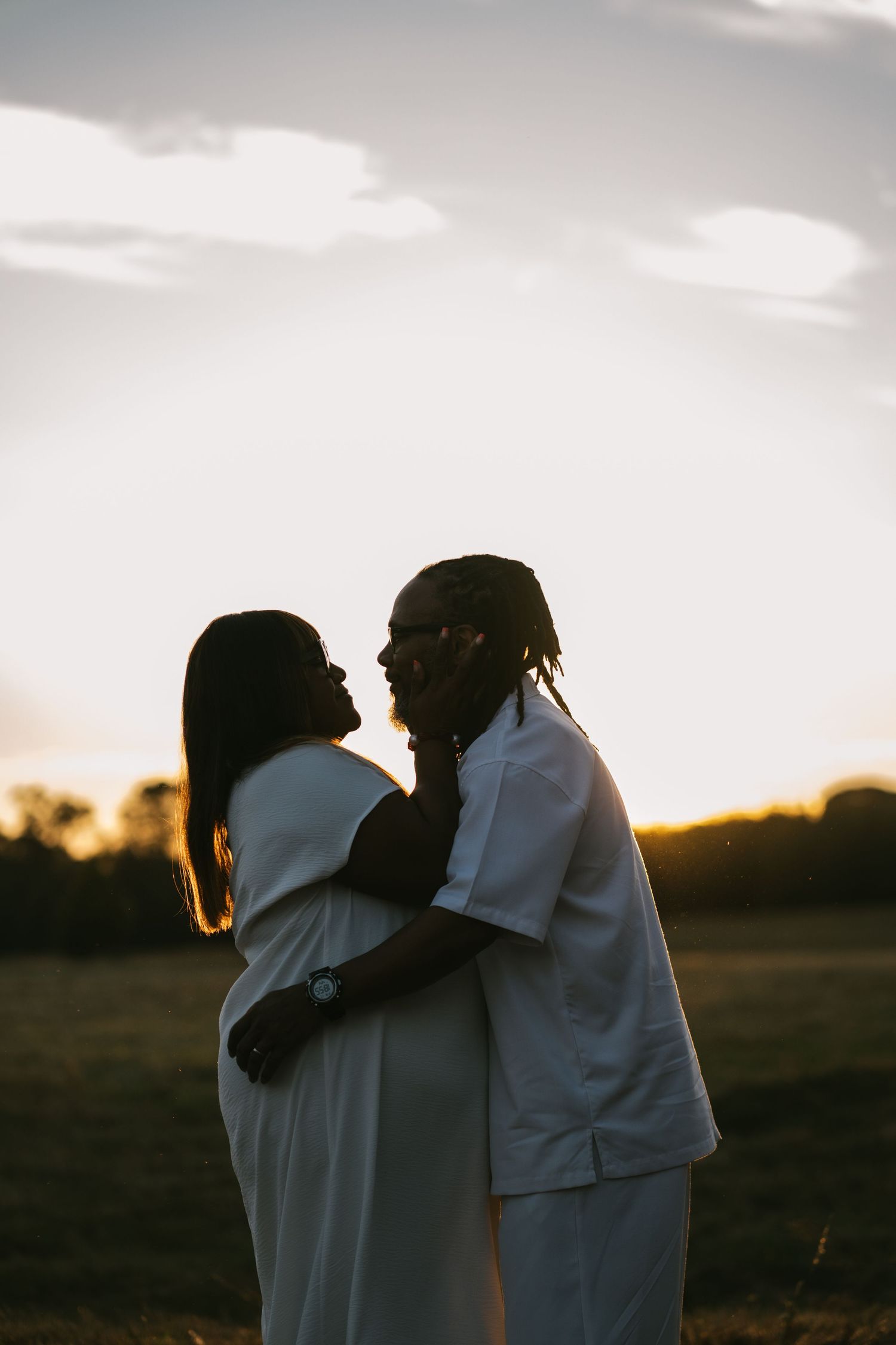Romantic silhouette of a couple embracing in a field during a breathtaking sunset.
