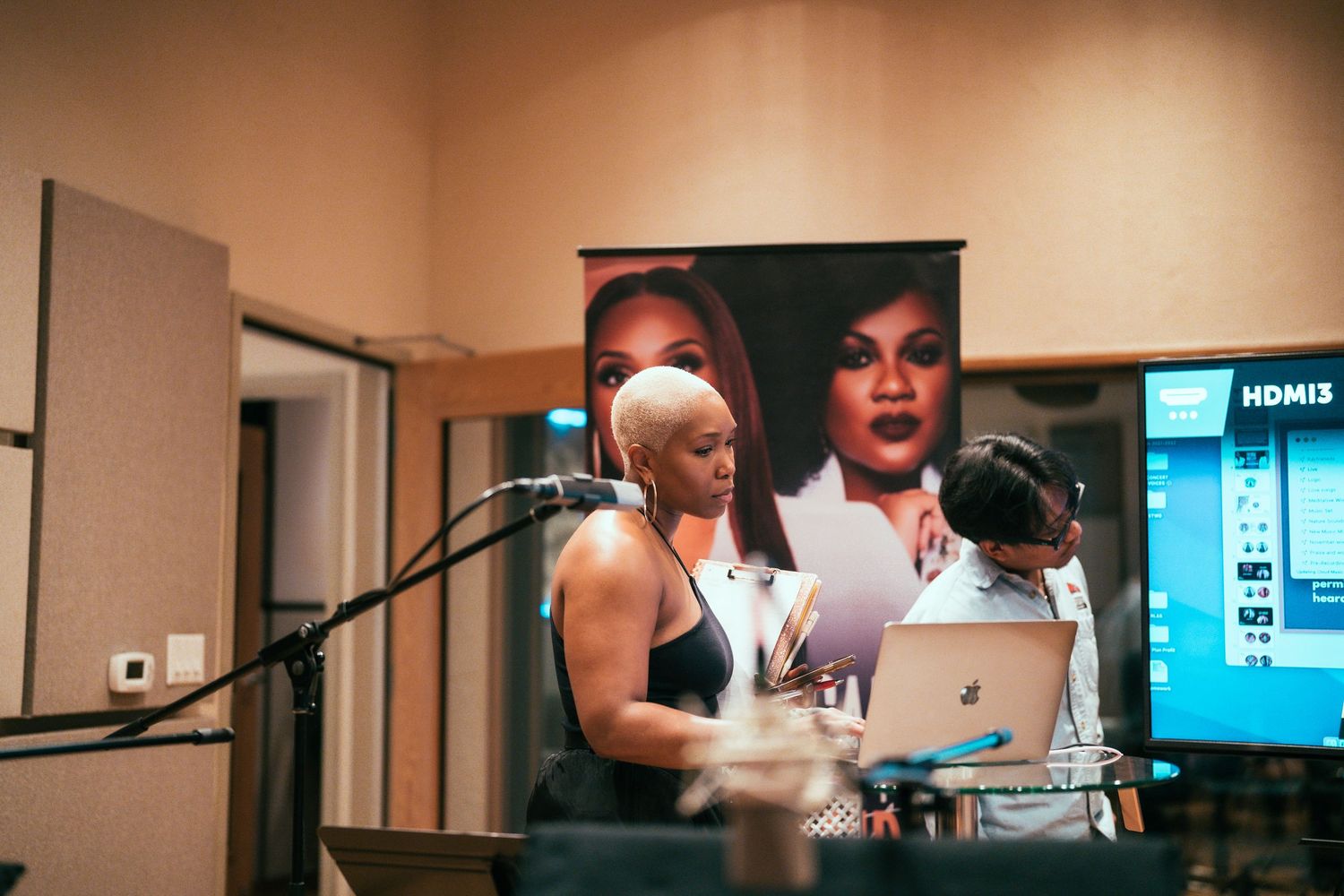 Woman presenting at music studio with laptop and microphone setup.