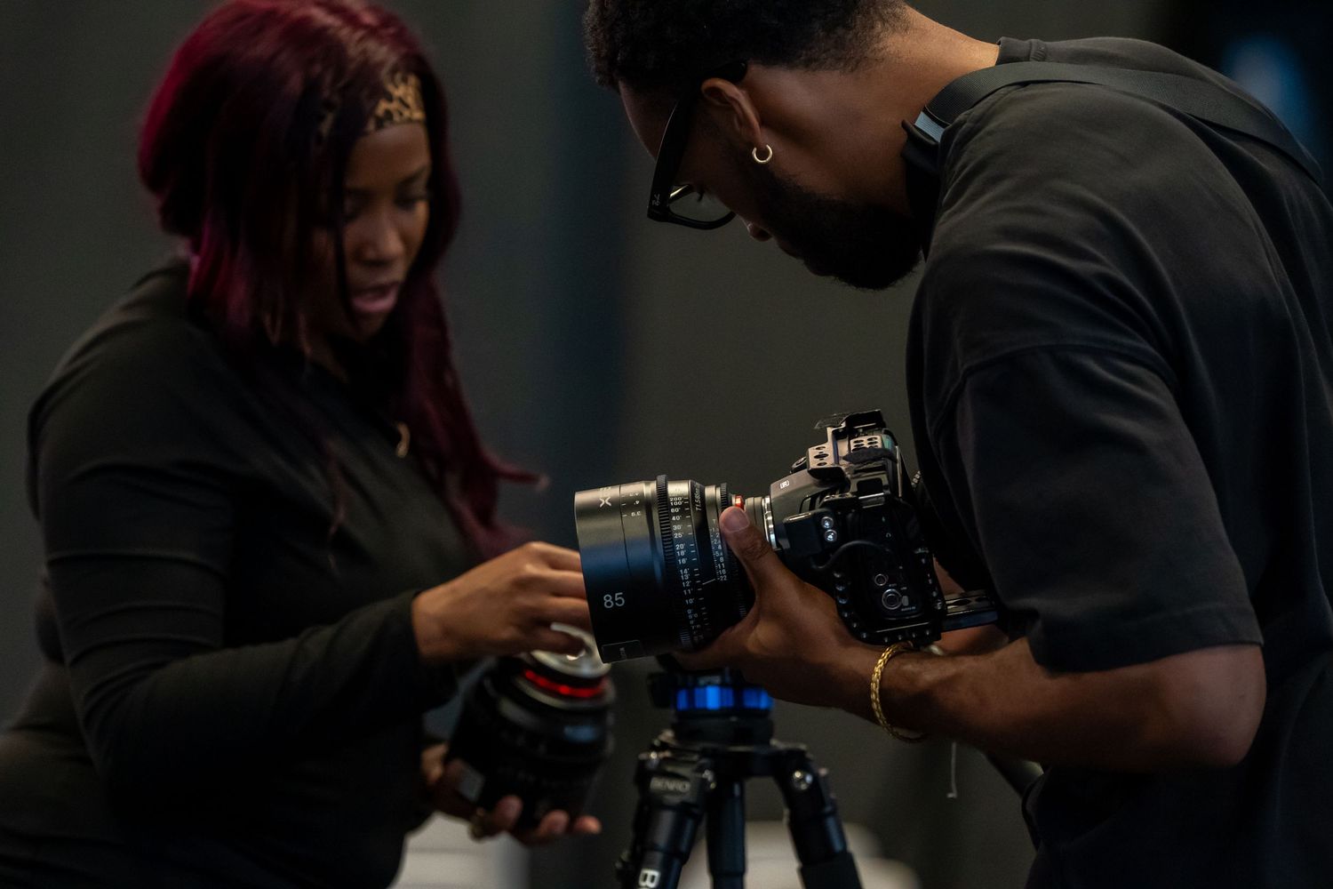 Two people examining a professional camera on a tripod during a film production workshop.