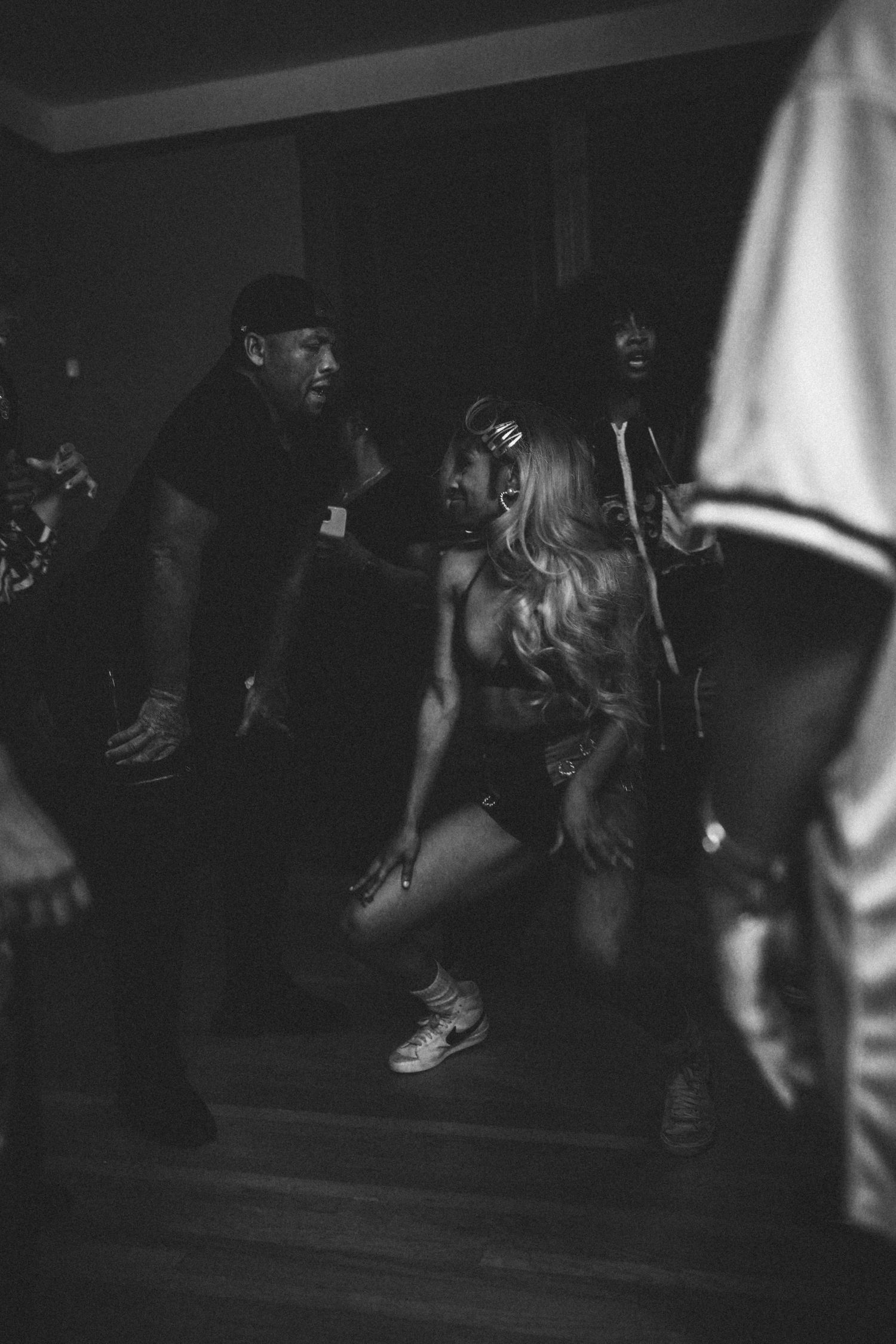 Black and white photo of a woman dancing at a dimly lit music video production set.