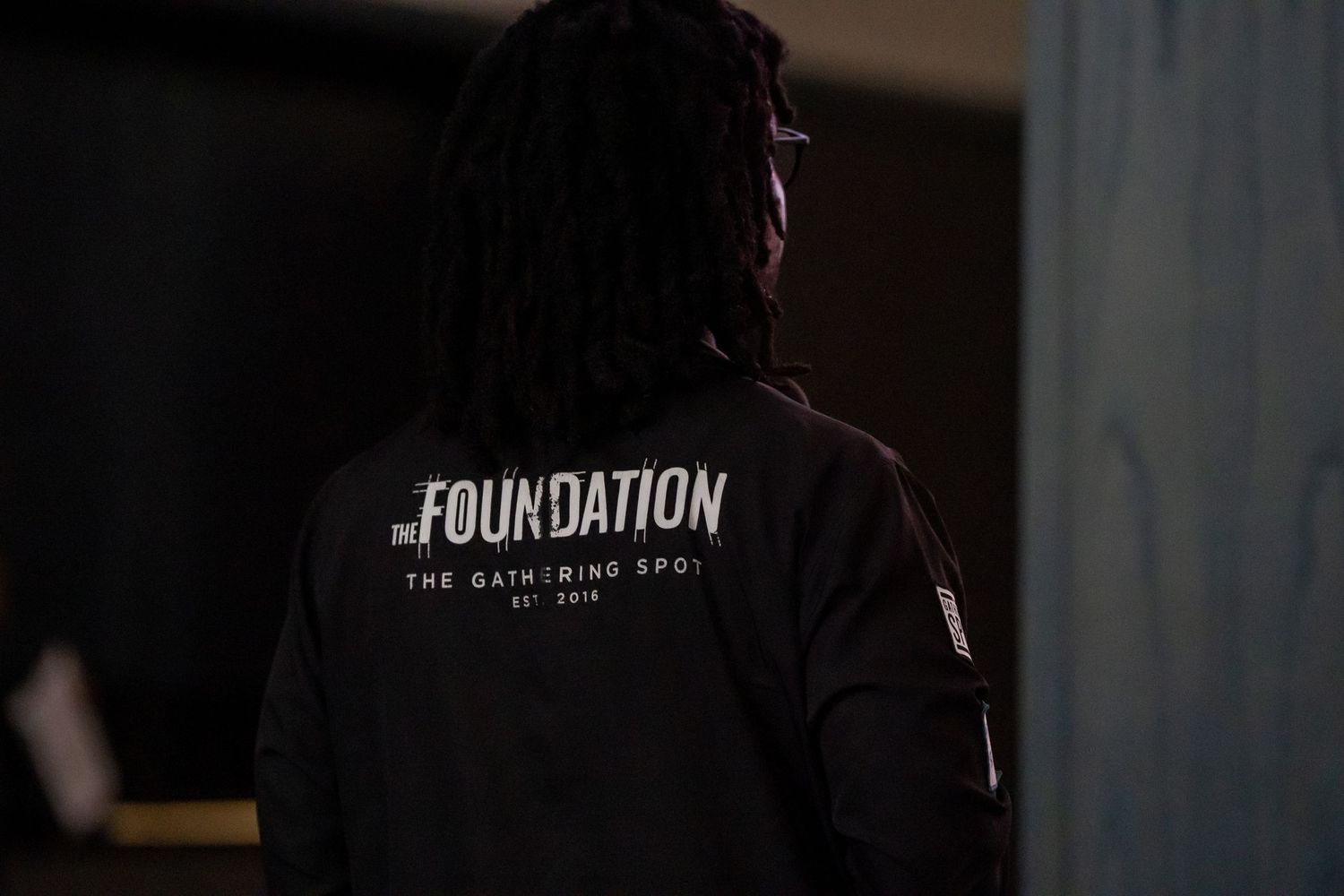 Person wearing The Foundation black hoodie at The Gathering Spot event.