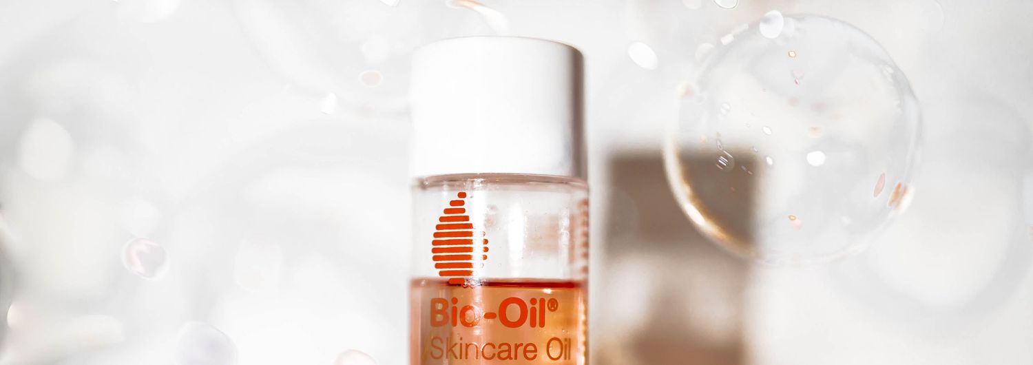 Bio-Oil Skincare Oil bottle surrounded by soft bokeh bubbles on a white background.
