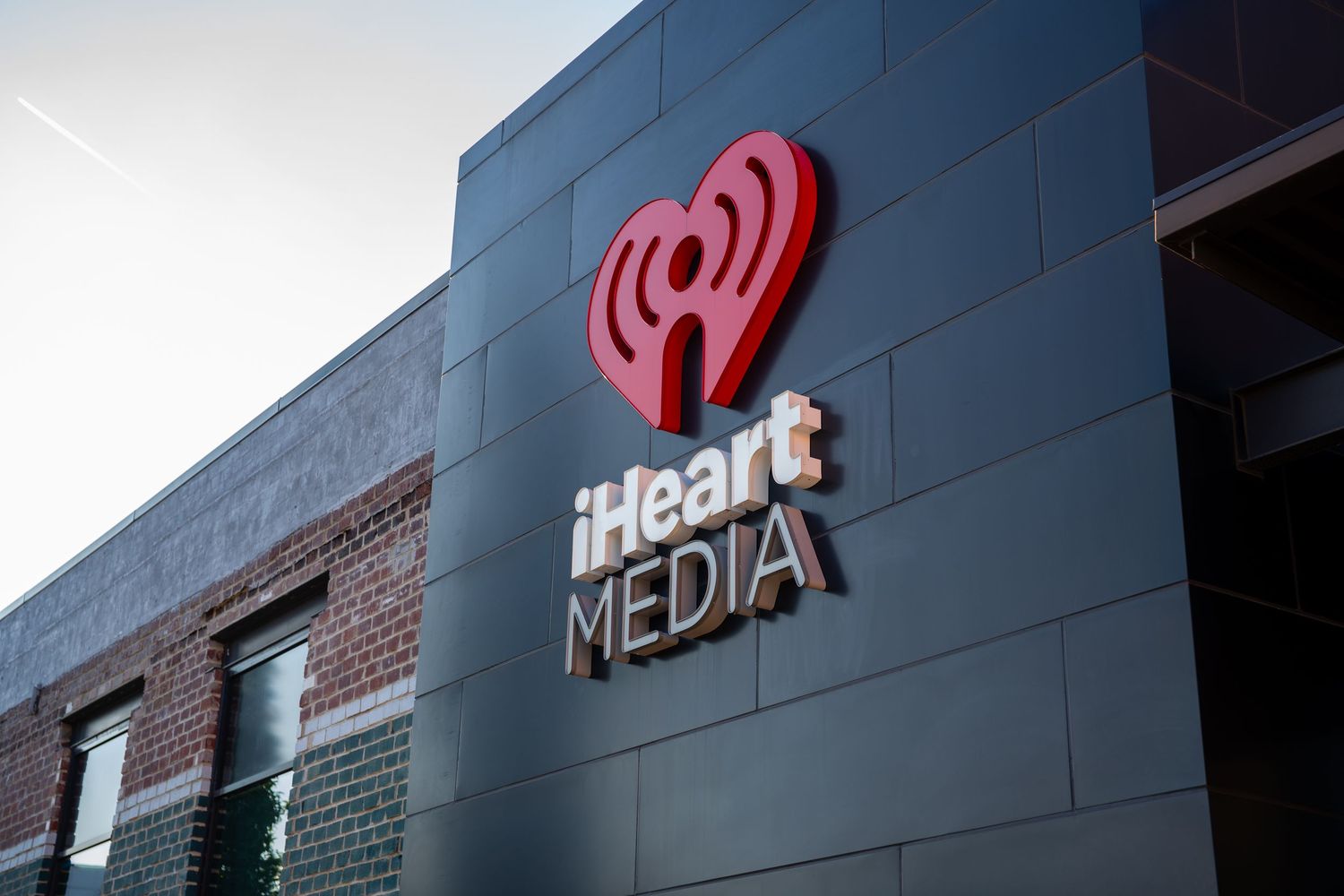 iHeartMedia logo sign mounted on a dark modern building exterior wall.