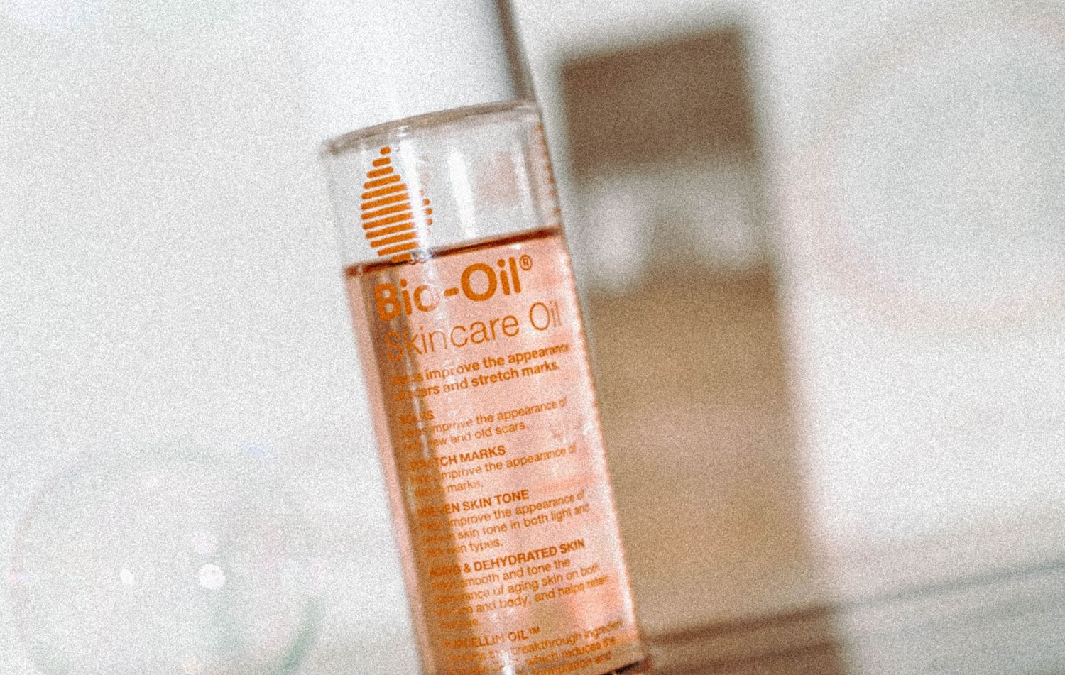 Bio-Oil Skincare Oil bottle lying on a reflective white surface with soft lighting.