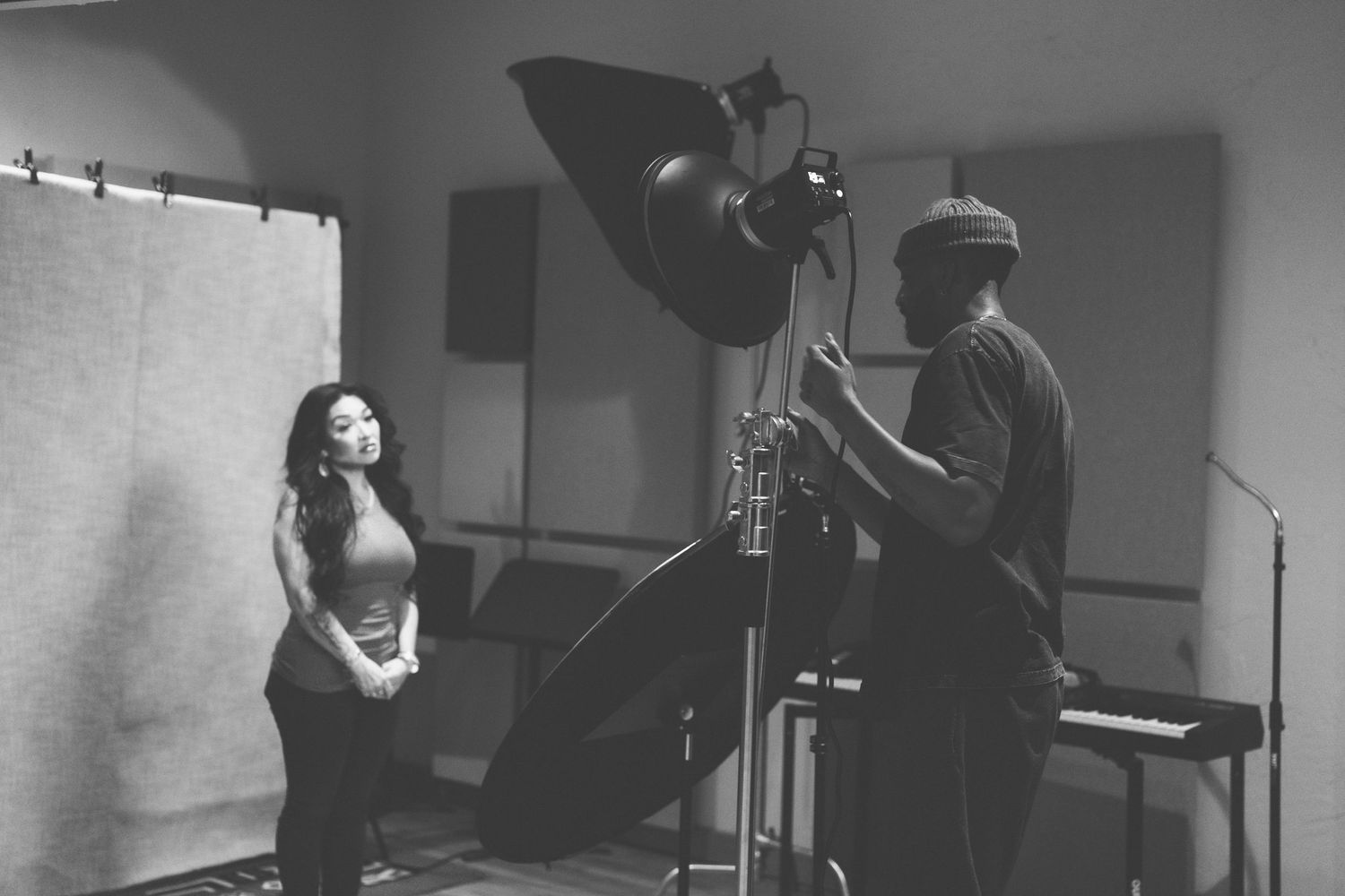 Black and white photo of two people in a professional recording studio with lighting equipment.