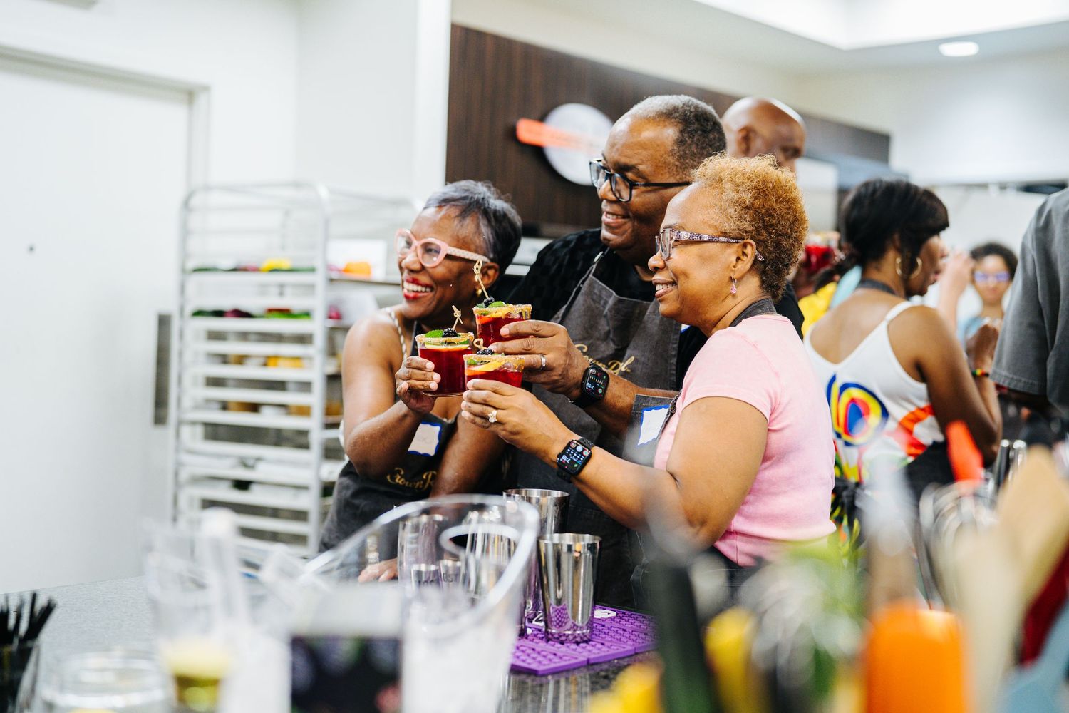 Group of people raise cocktail glasses in a toast at a Crown Royal mixology event.