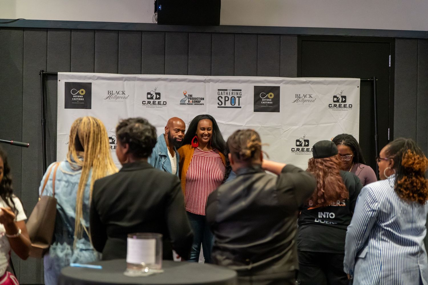 Group of people posing for photos at CREED branded step and repeat backdrop.