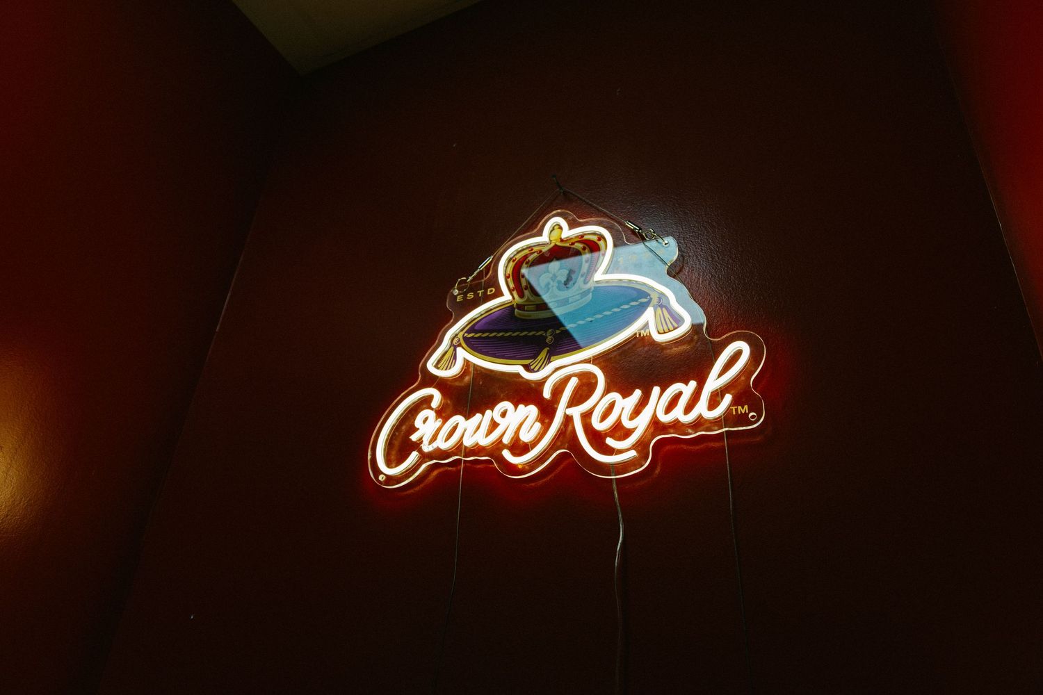Crown Royal neon sign glowing on a dark wall.