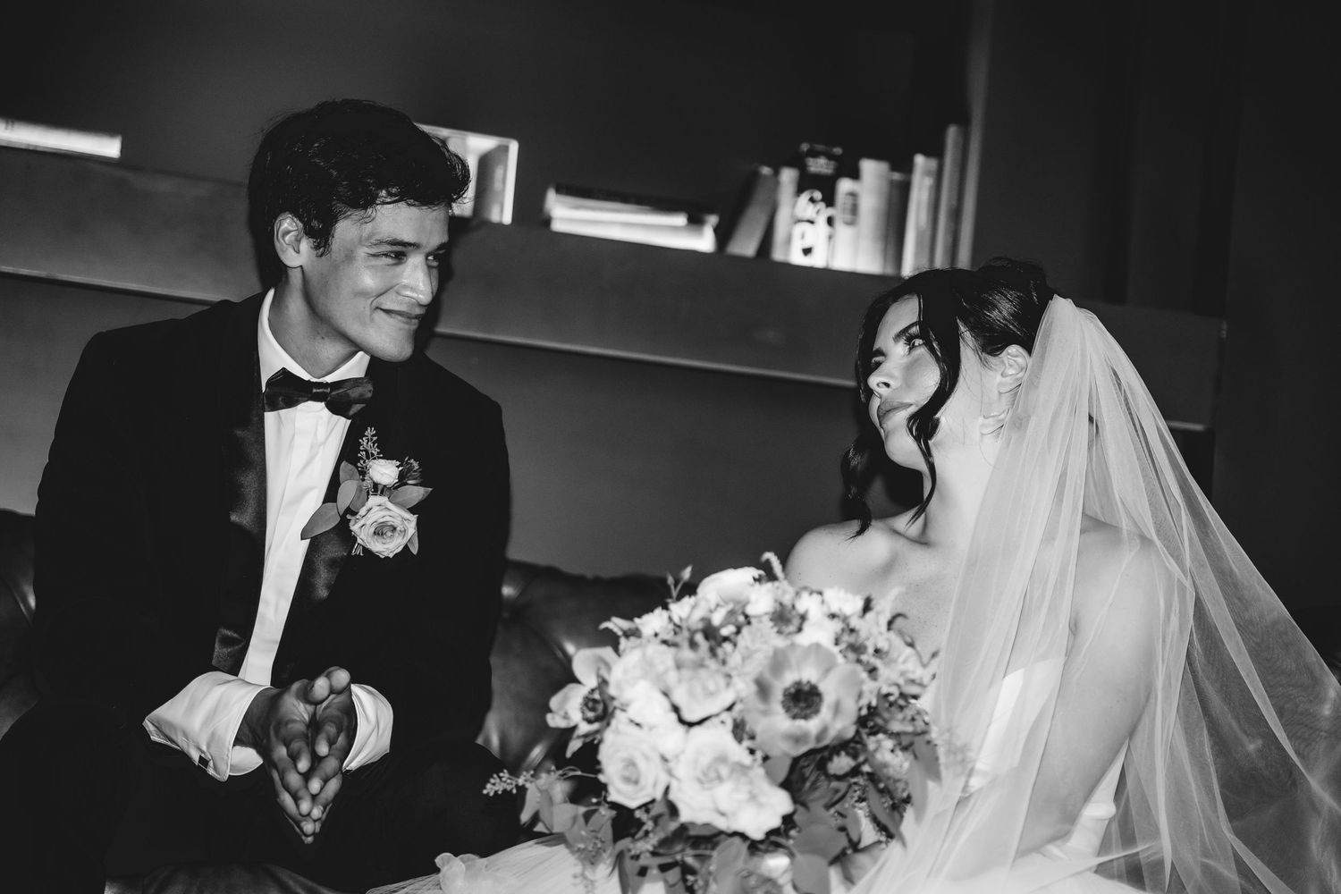 Elegant black and white wedding photo of bride and groom smiling at each other.