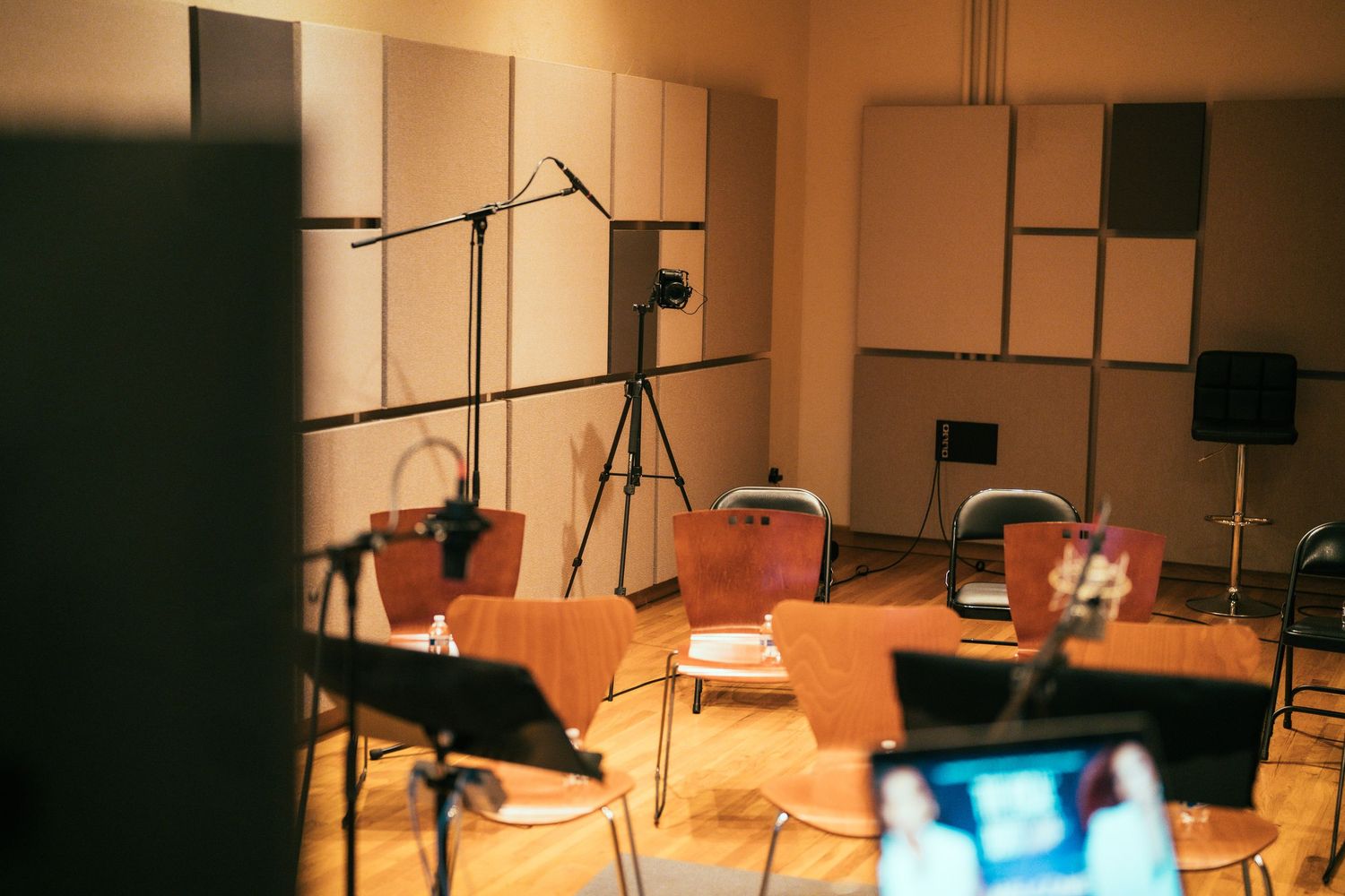 Empty recording studio with acoustic panels, microphone stands, and chairs.