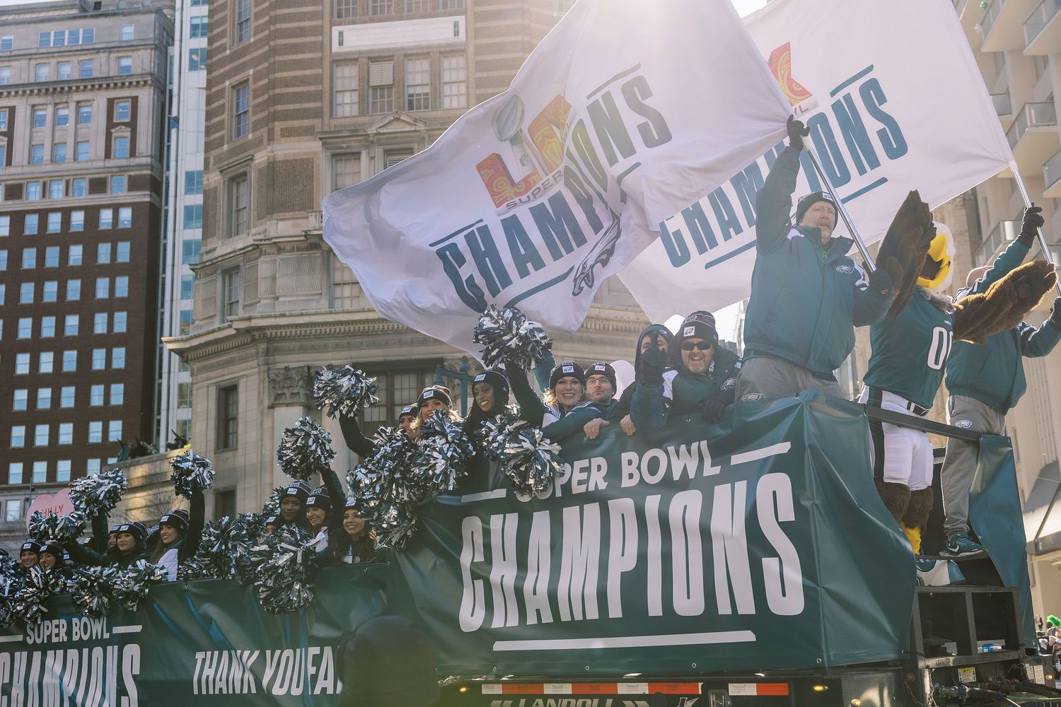 Super Bowl champions celebration with flags and confetti in downtown urban setting.