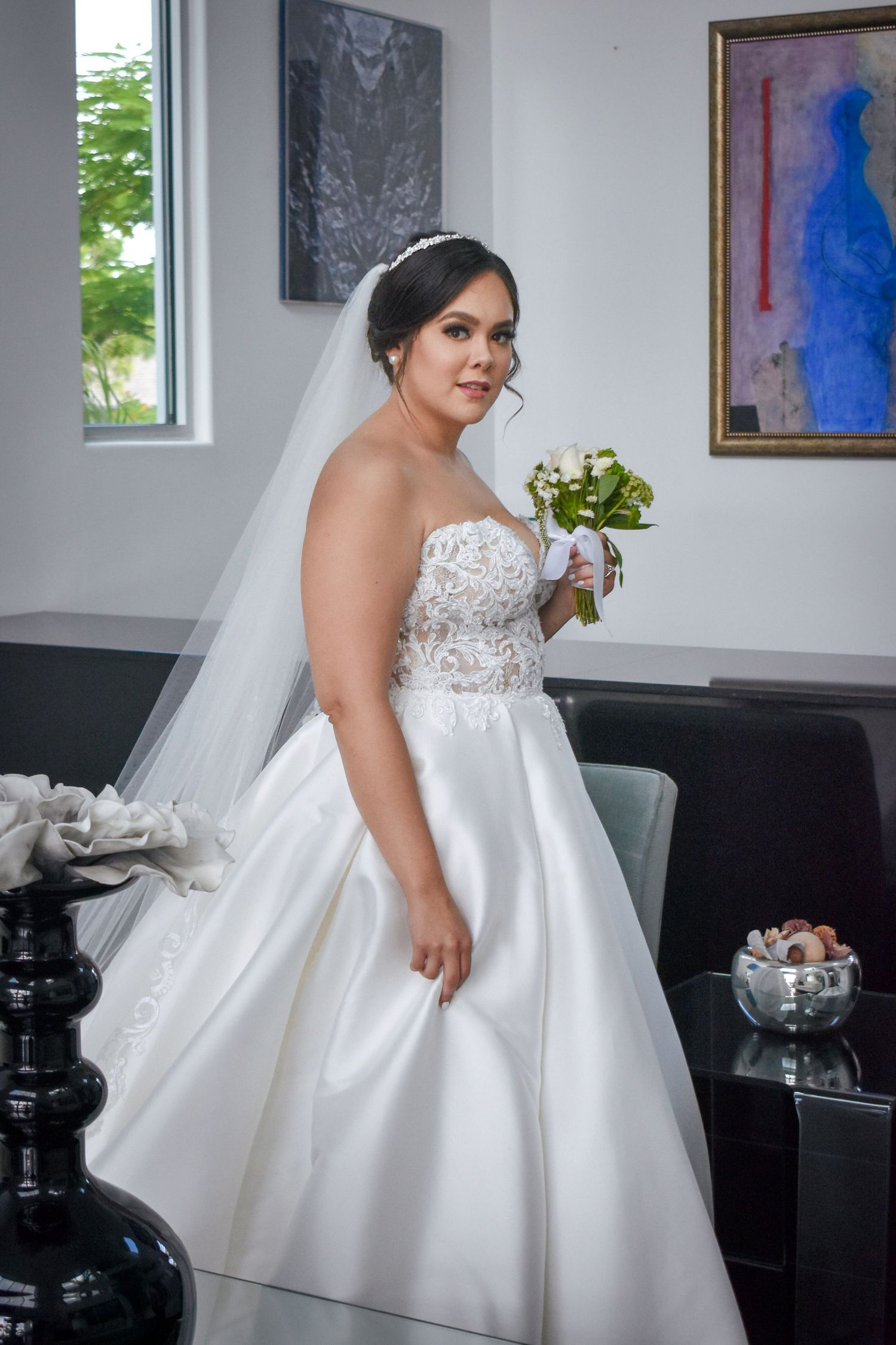Bridal portrait in Brownsville Texas with bride in strapless lace gown holding bouquet indoors