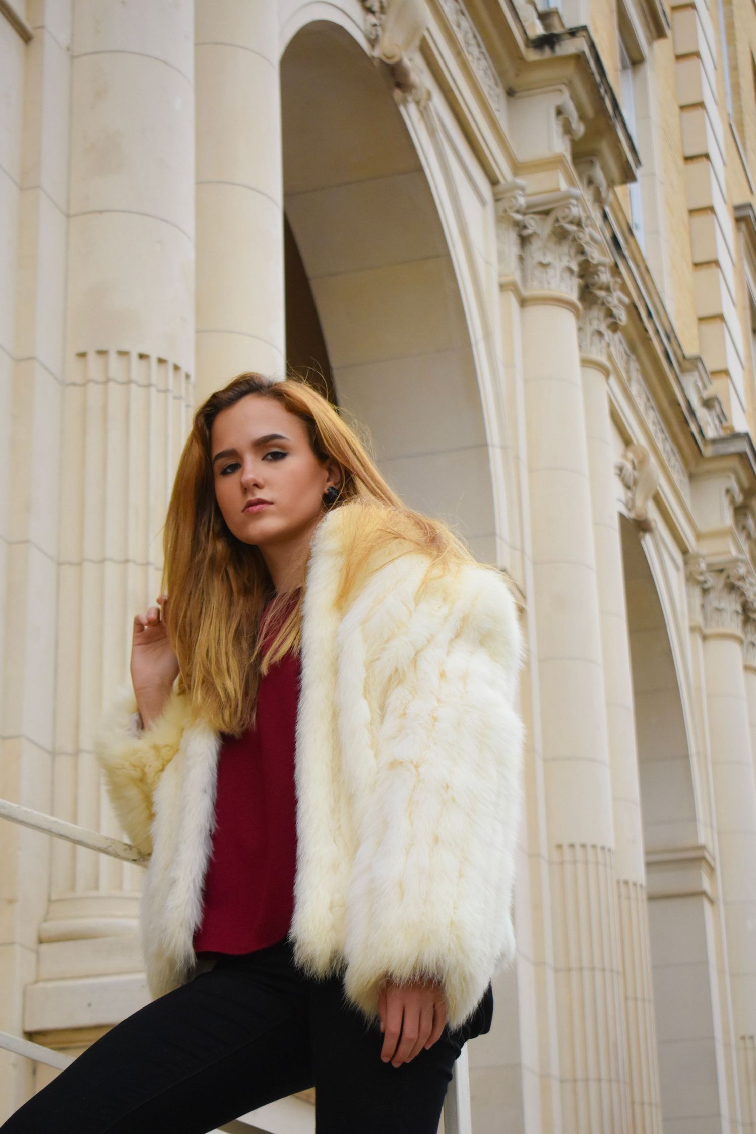 Portrait photography in Brownsville Texas of woman in white faux fur coat by classical columns