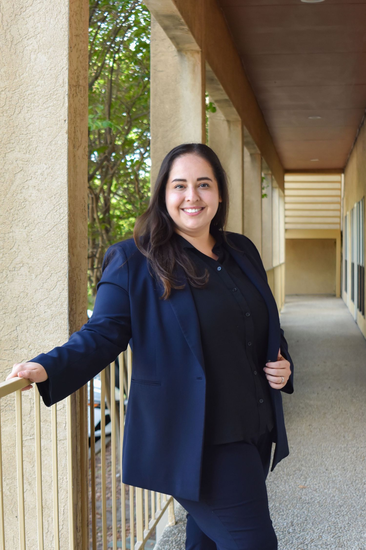 Professional outdoor portrait of San Antonio lawyer in navy blazer on office walkway