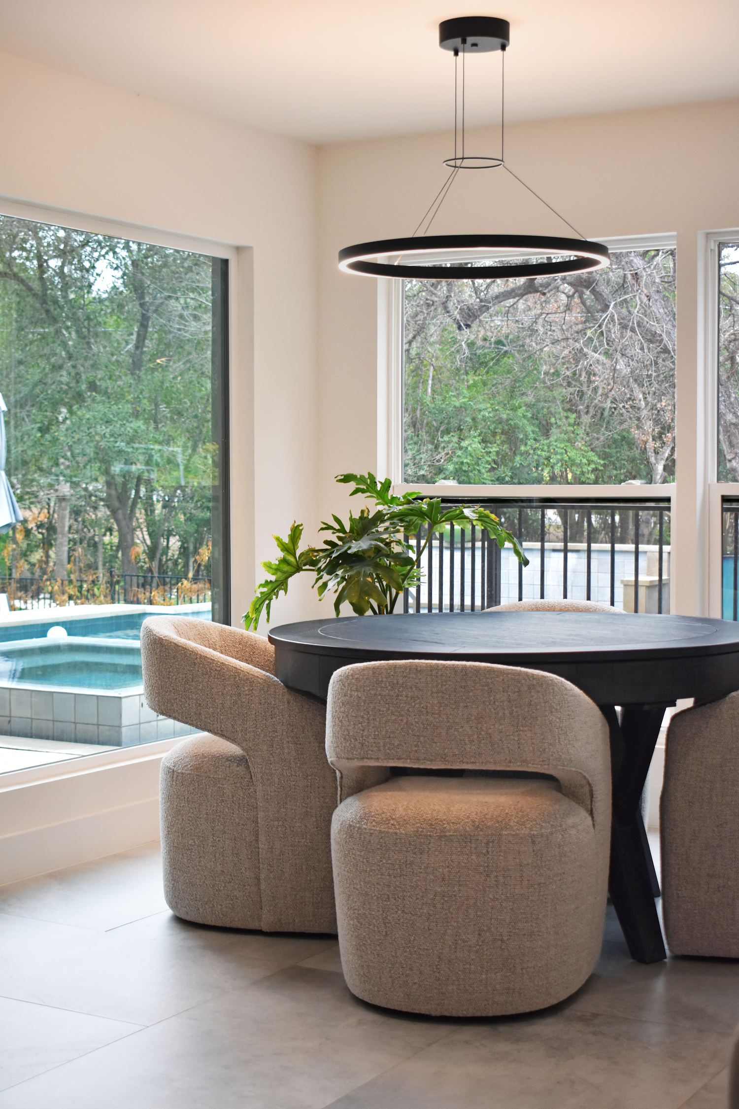 Residential dining area interior in San Antonio with round table and pool view through large windows