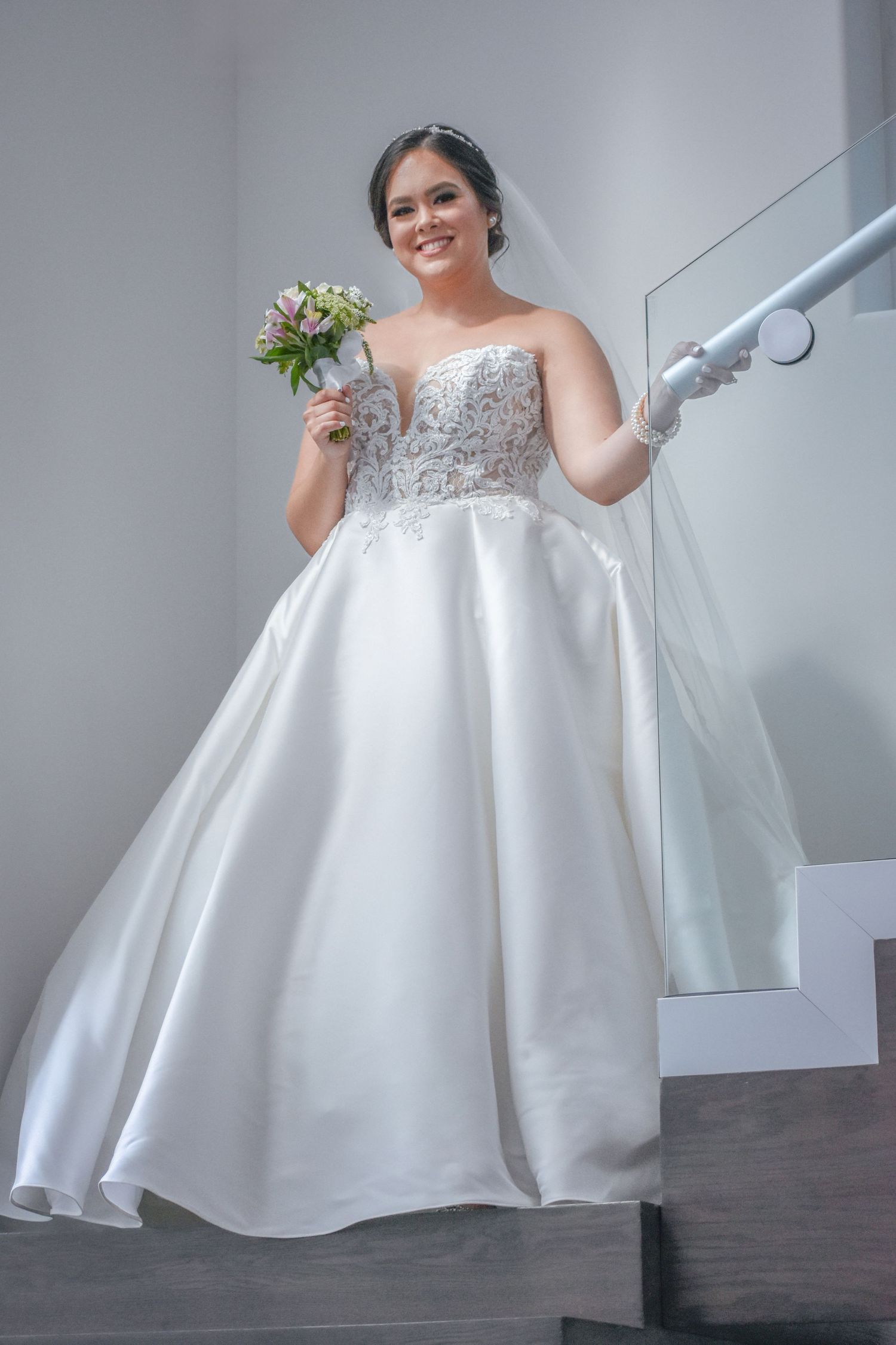 Bridal portrait in Brownsville Texas with bride in lace ballgown holding bouquet on staircase