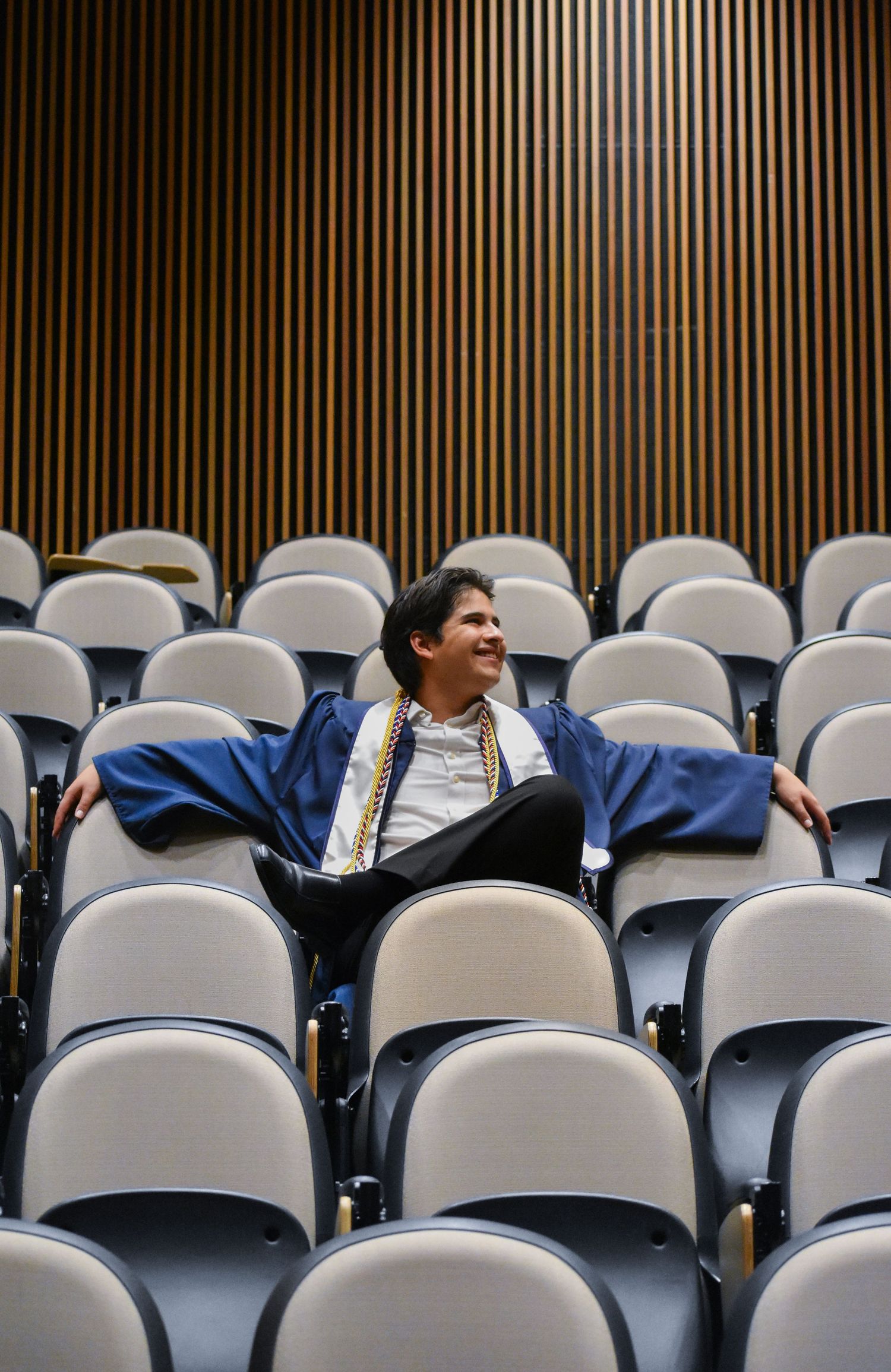 UTSA graduation portrait seated in campus lecture hall auditorium in San Antonio