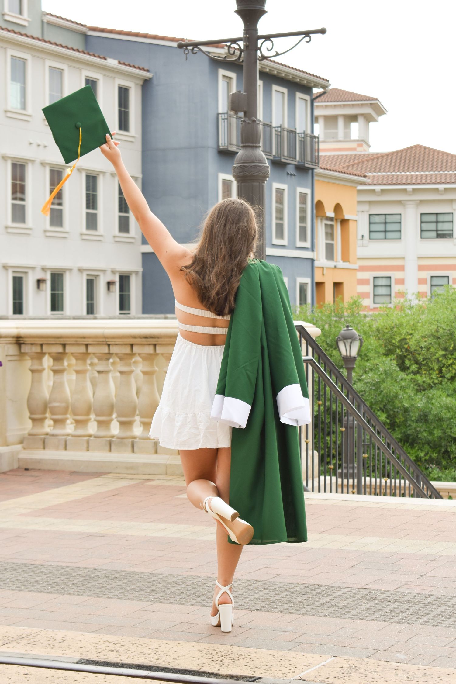 High school graduation portrait at The Eilan Hotel in San Antonio with graduate celebrating in green gown