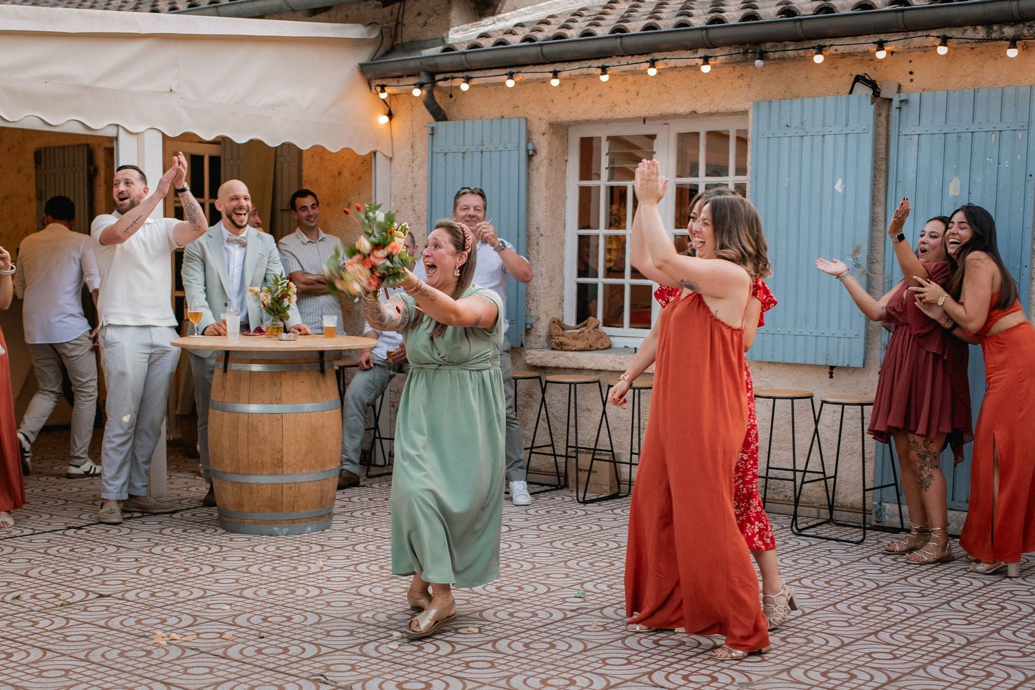 Guests dancing and celebrating outdoors at a rustic French wedding venue with string lights and wine barrels.
