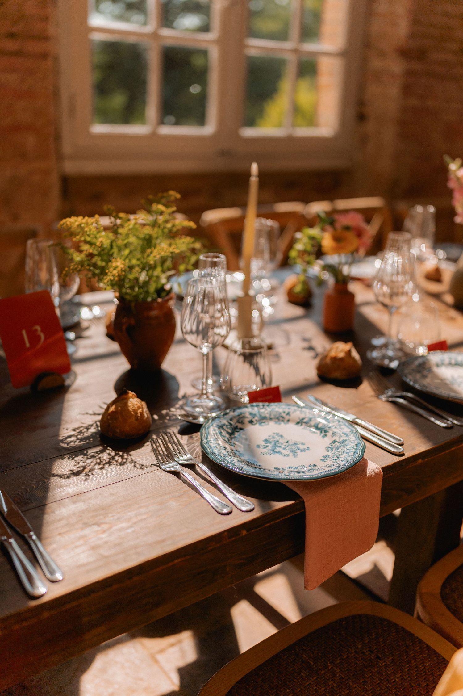 Rustic wedding table setting with blue floral plates, candles, and autumn decor.