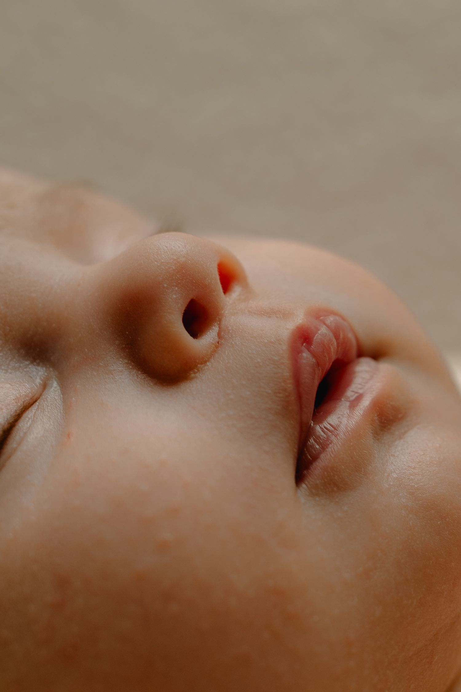 Extreme close-up of a sleeping newborns face showing delicate features and soft skin.